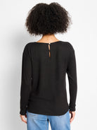 Black long-sleeved top, relaxed fit. Features a wide back neckline with a keyhole opening secured by a white button.