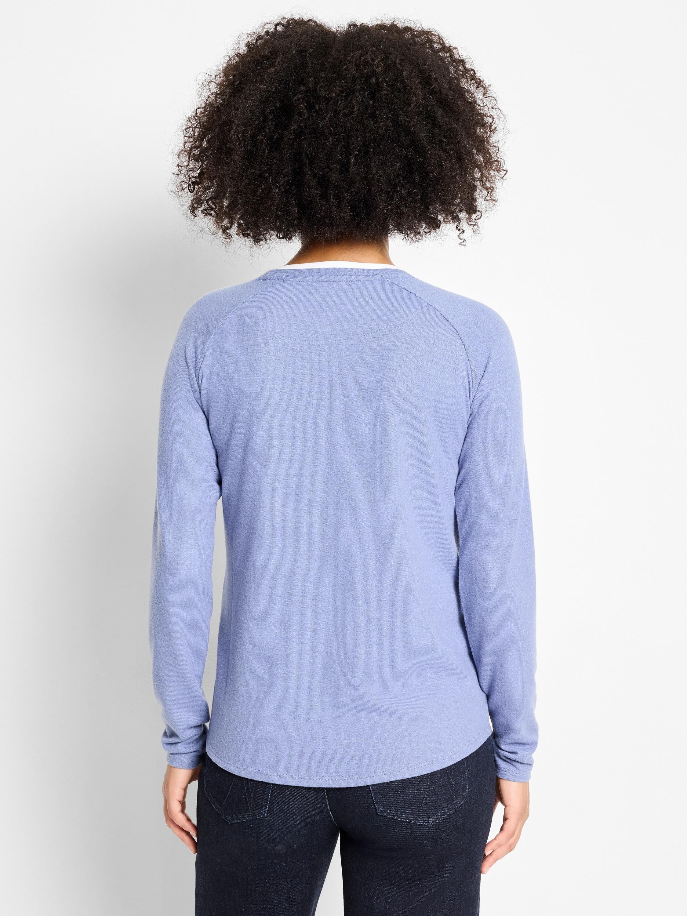 Back view of a periwinkle long-sleeve top. White inner layer visible at neck, rounded hem. Relaxed fit.