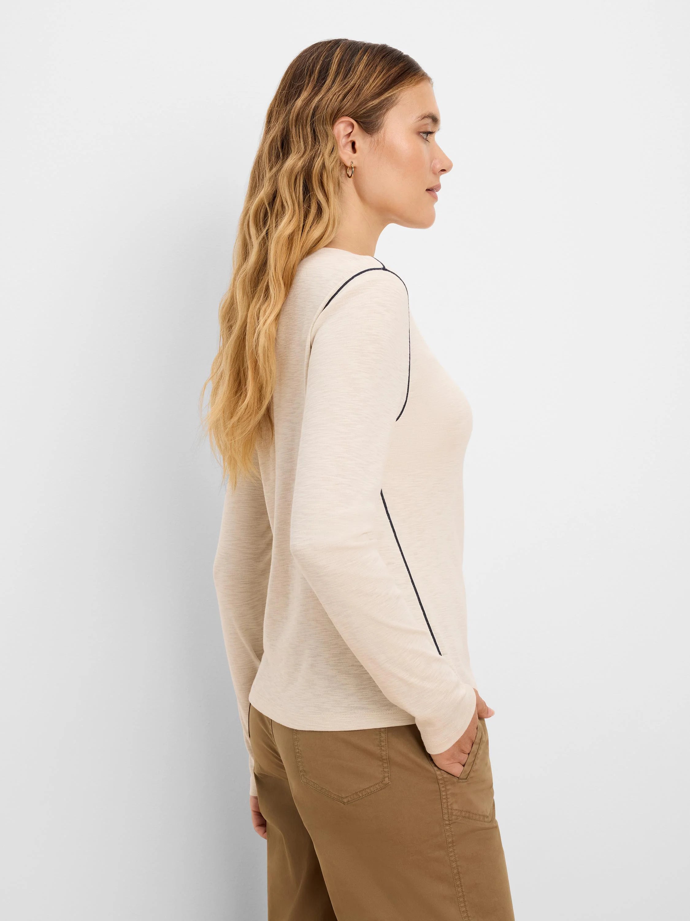 Pale beige long sleeve tee with dark piping on shoulder and side seams.