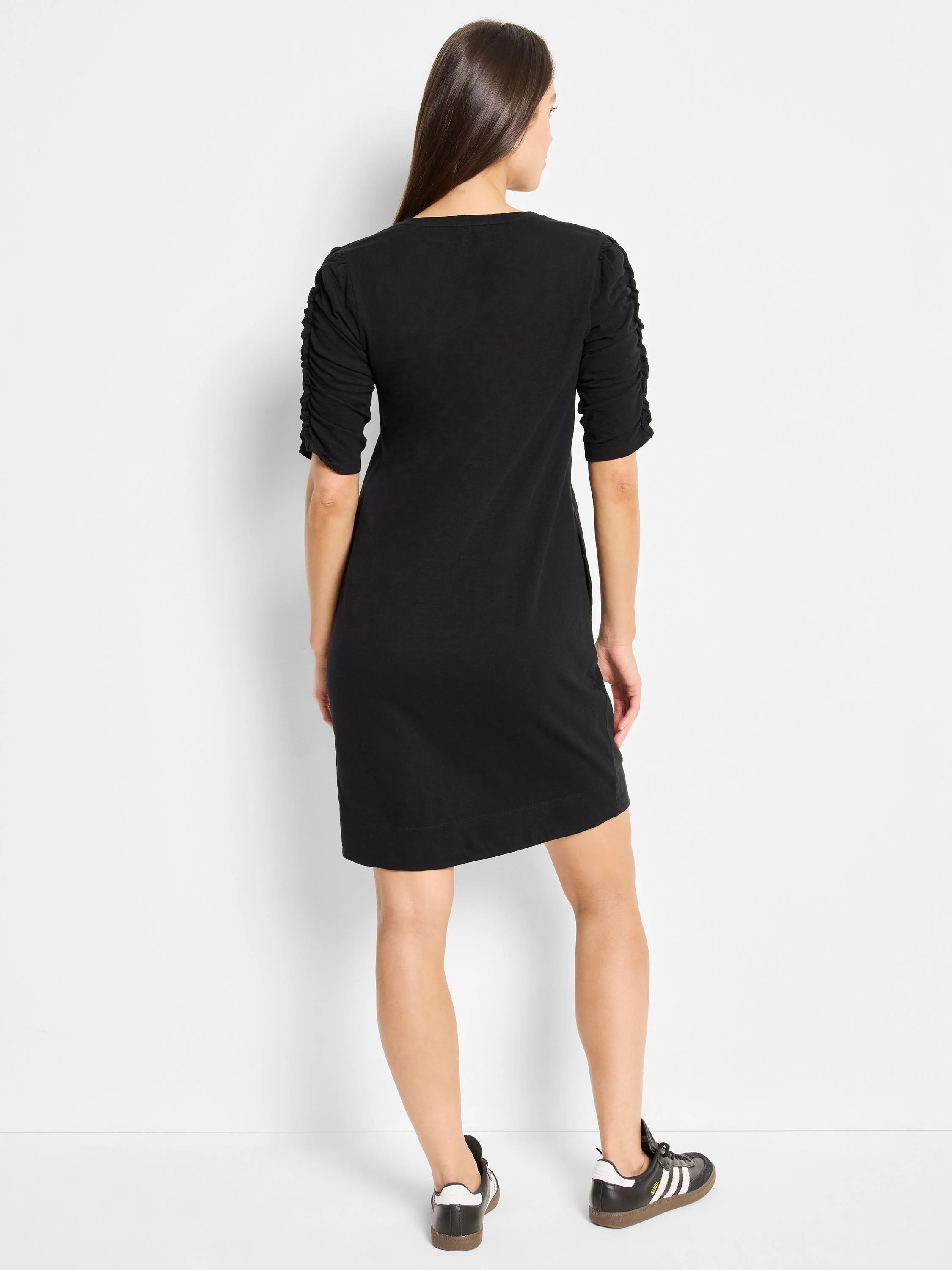 Black mini dress, elbow-length sleeves with ruched detailing. Straight, A-line silhouette.