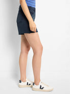 Dark-wash denim shorts; frayed hem.  Side profile shows fit and cut.
