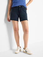 Dark wash denim shorts; raw hem.  Model is wearing them with white sneakers.