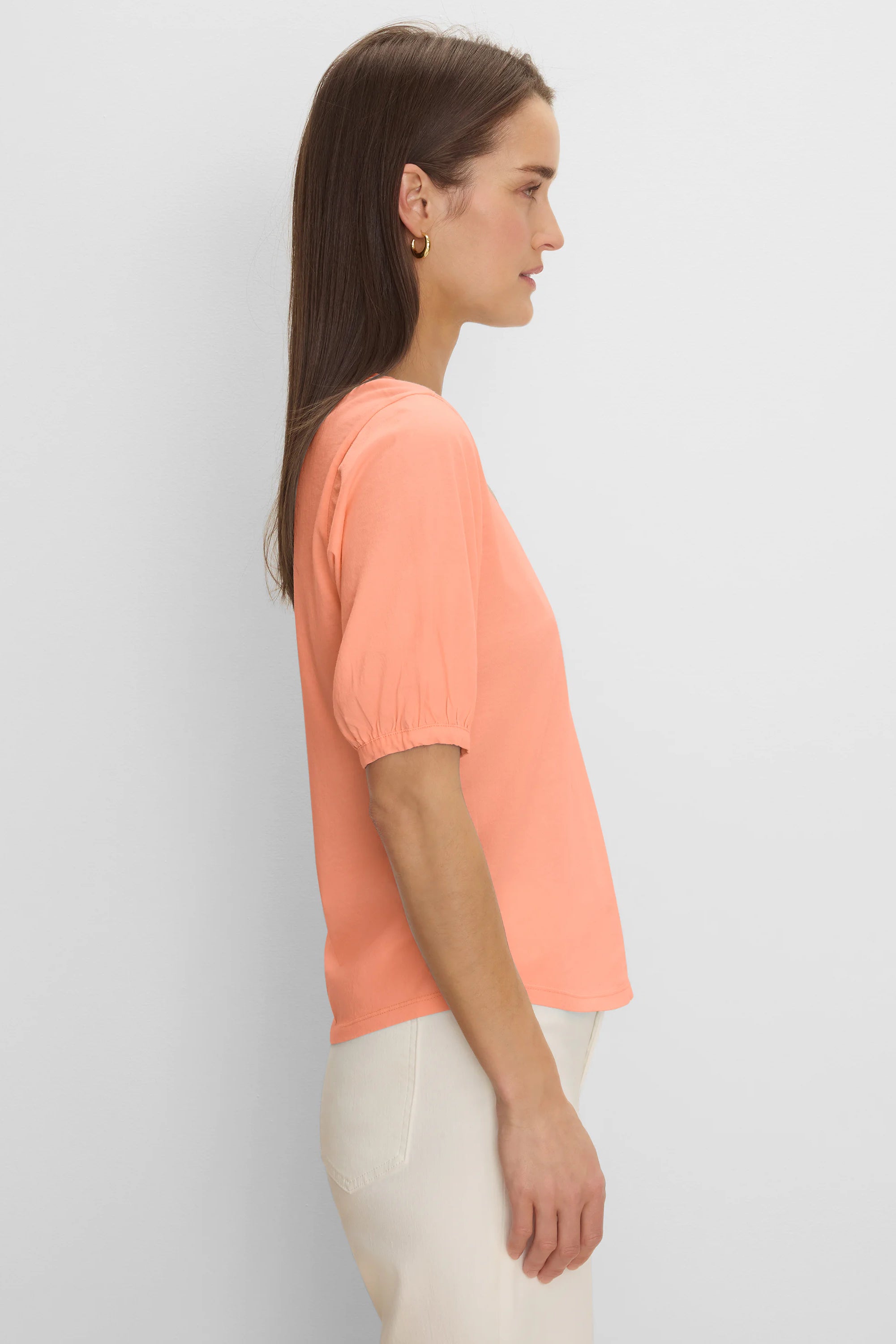 Peach elbow sleeve tee with gathered cuffs, worn by a model in profile.