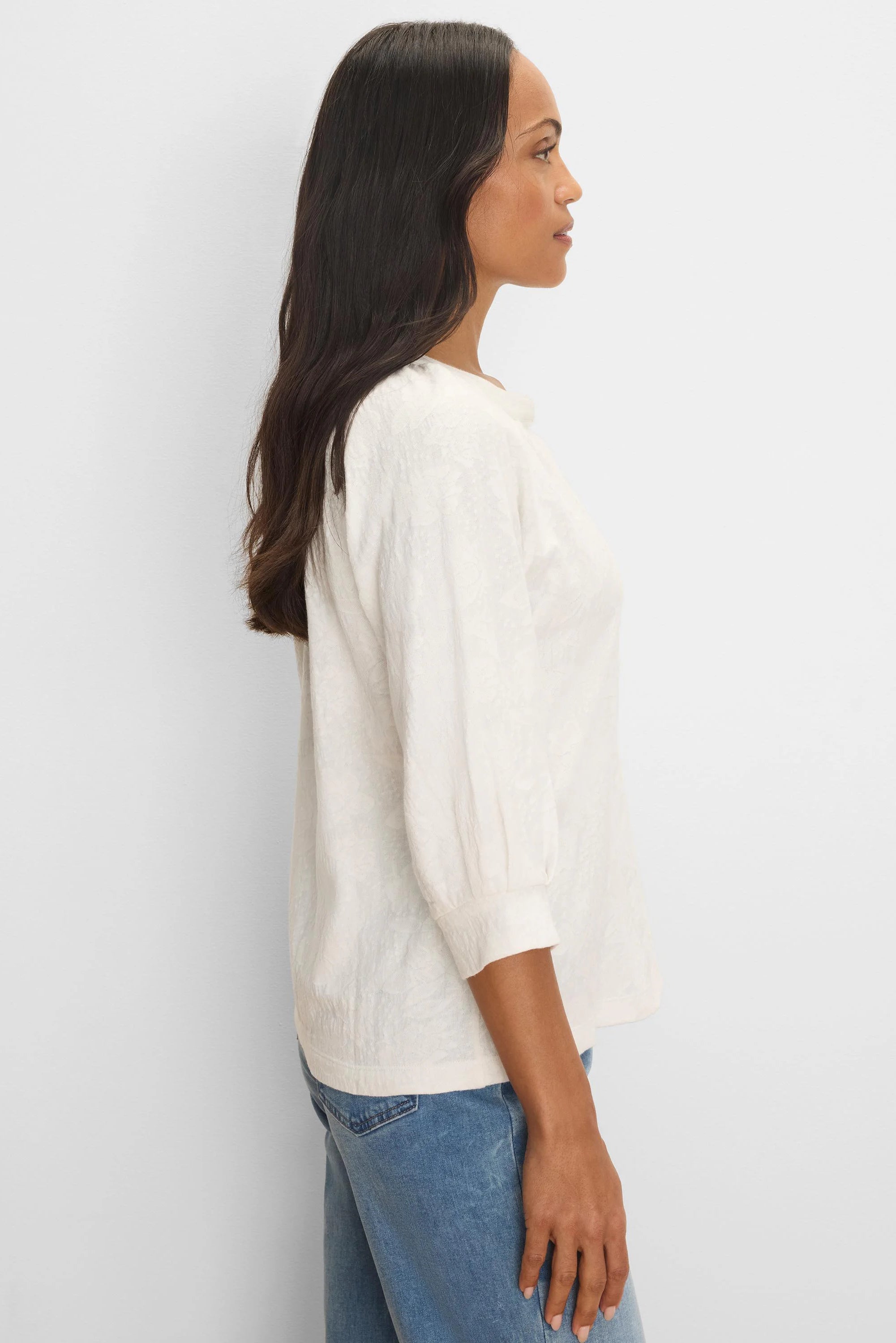 Cream-colored knit top with subtle pattern, relaxed fit, and 3/4 length sleeves with gathered cuffs. Model shown from side.