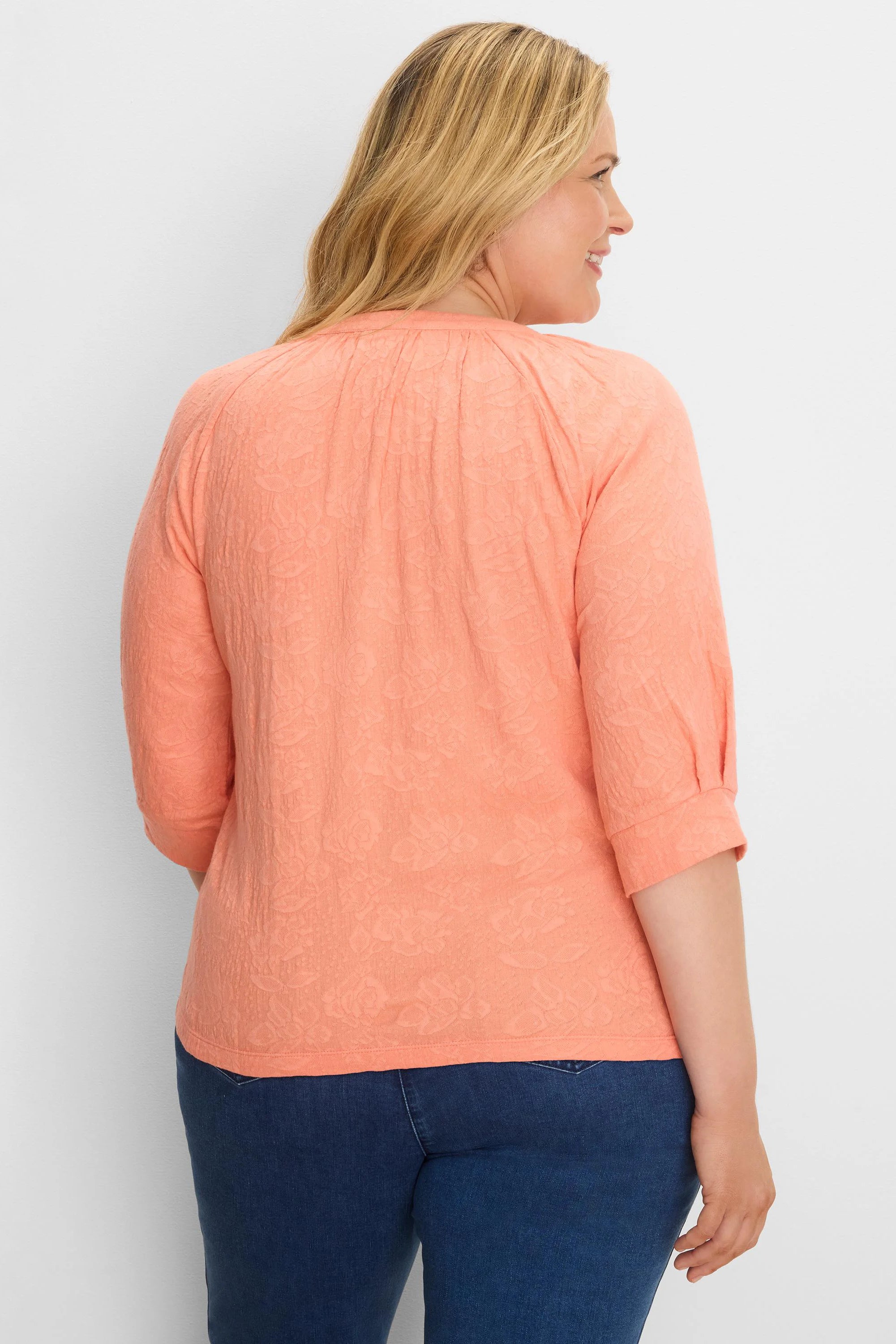 Peach lace knit top with a subtle floral pattern, featuring 3/4 cuffed sleeves. Model is shown from the back.
