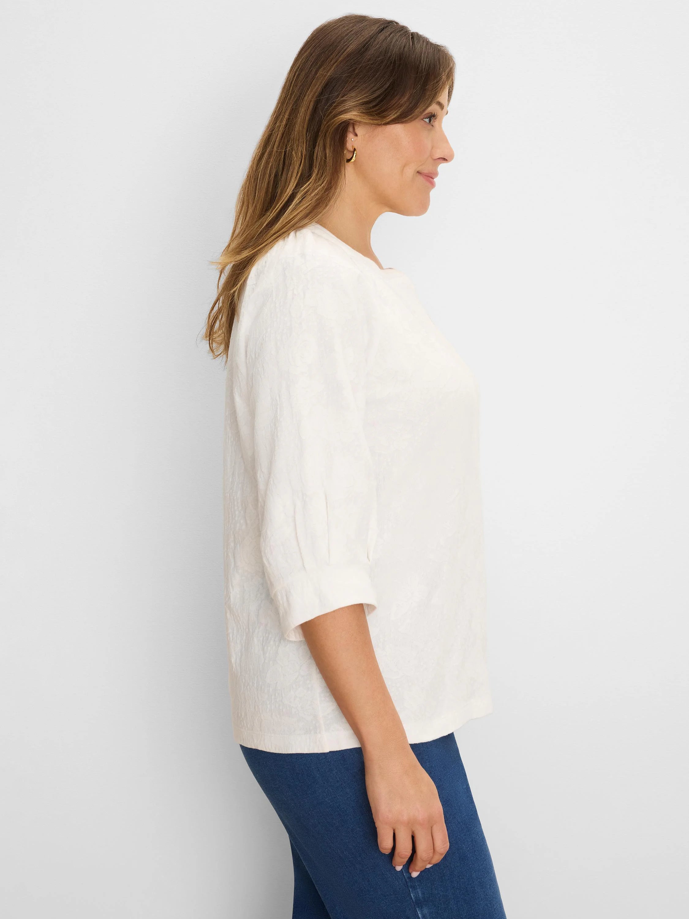 Off-white lace knit split neck top with 3/4 sleeves, worn by a model in a side profile.