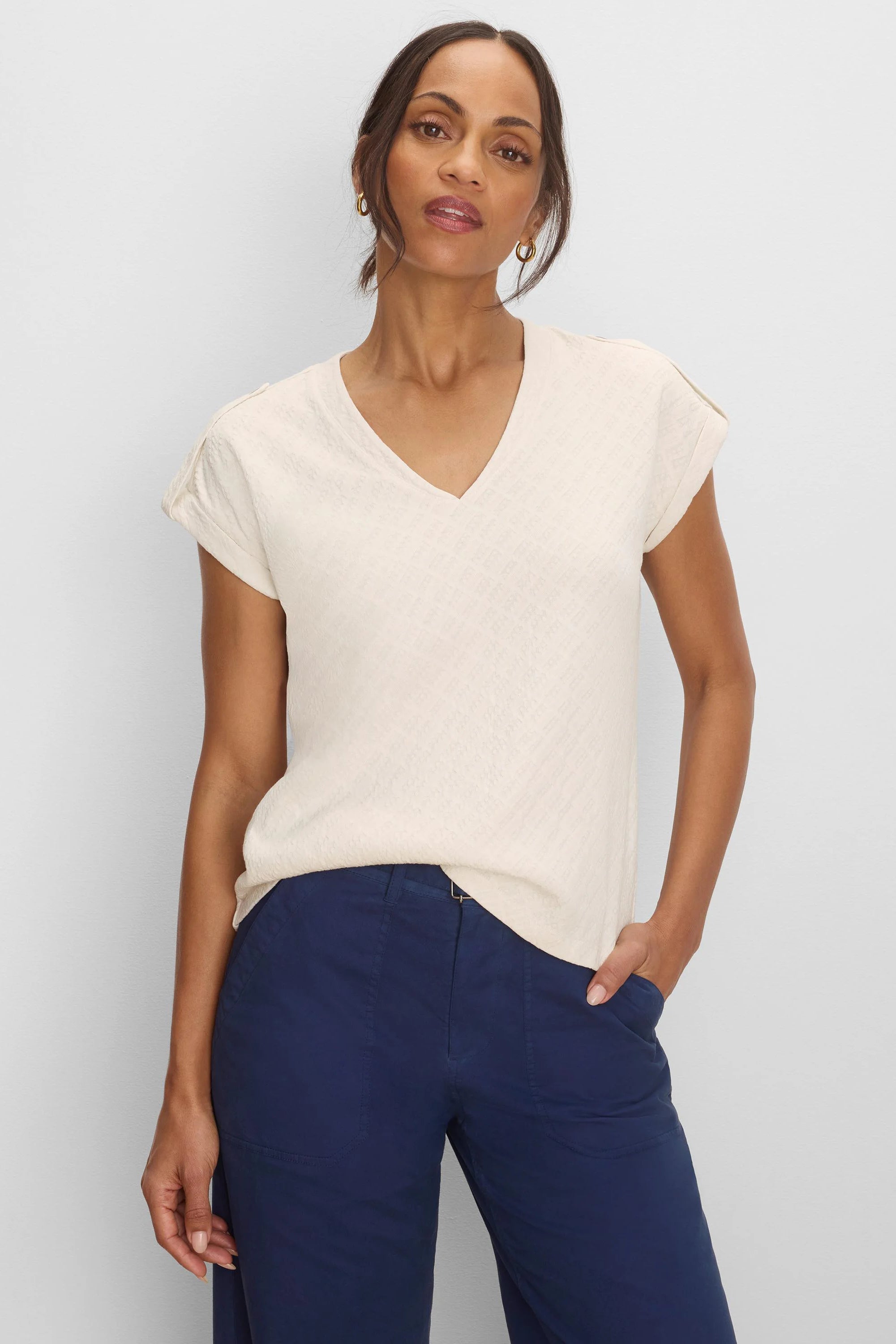 Light cream V-neck tee with subtle geometric lace knit texture and rolled cap sleeves.