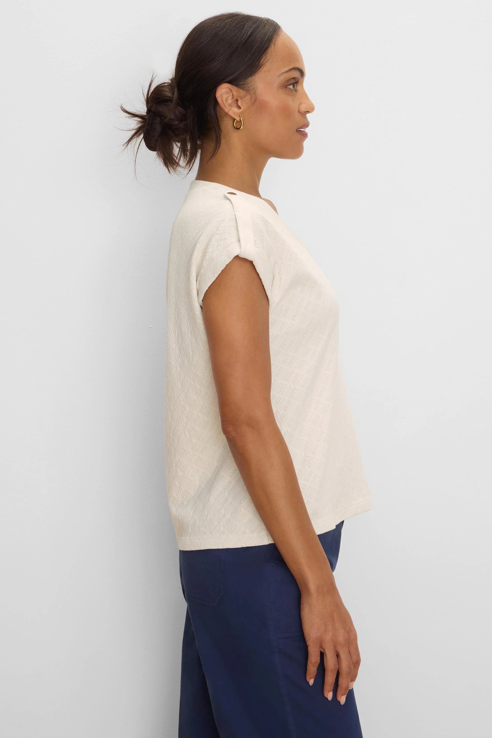 Off-white lace knit cap sleeve tee with buttoned shoulder tabs, worn by model.