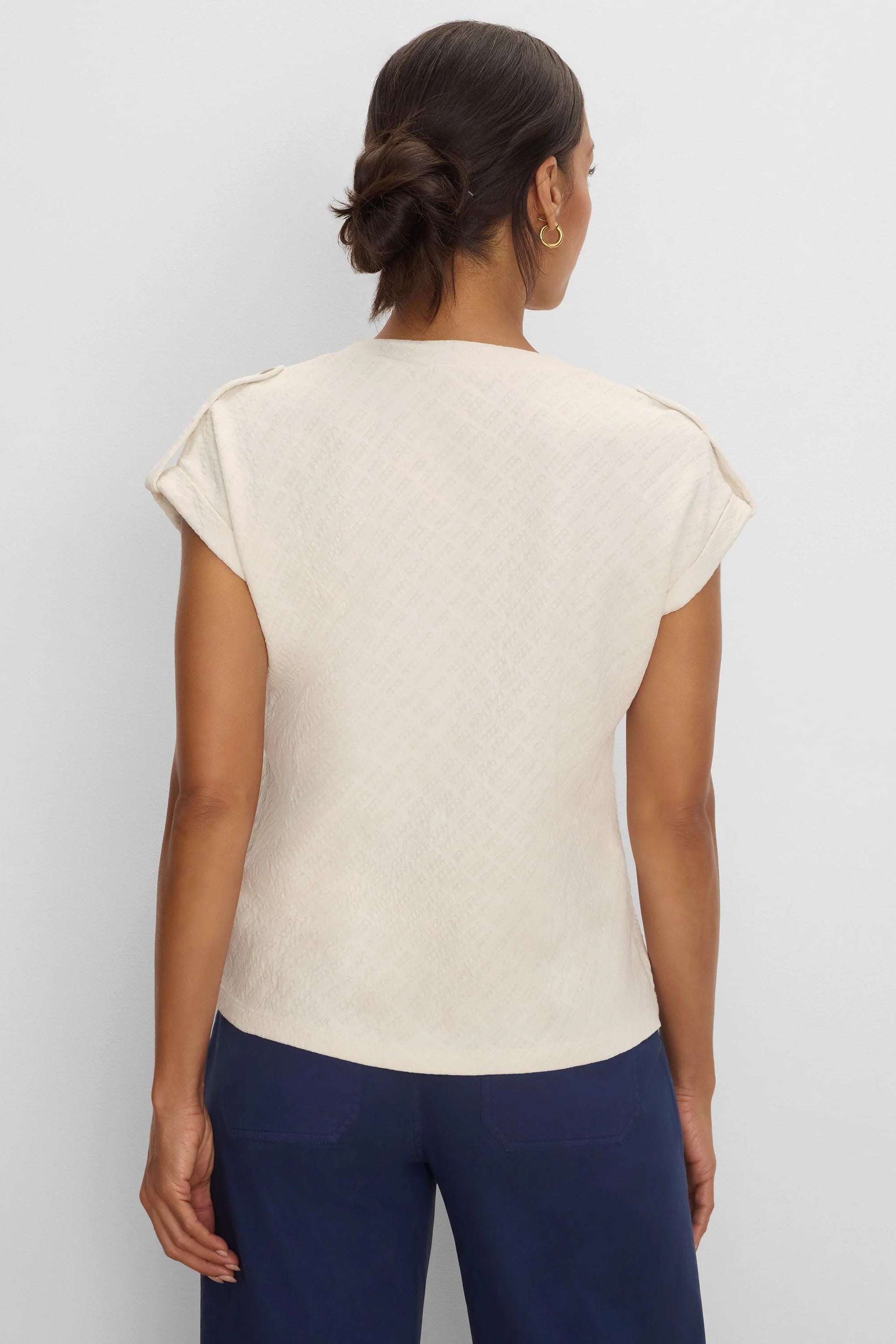 Cream lace knit tee with raised geometric texture and cap sleeves, shown from the back on model.