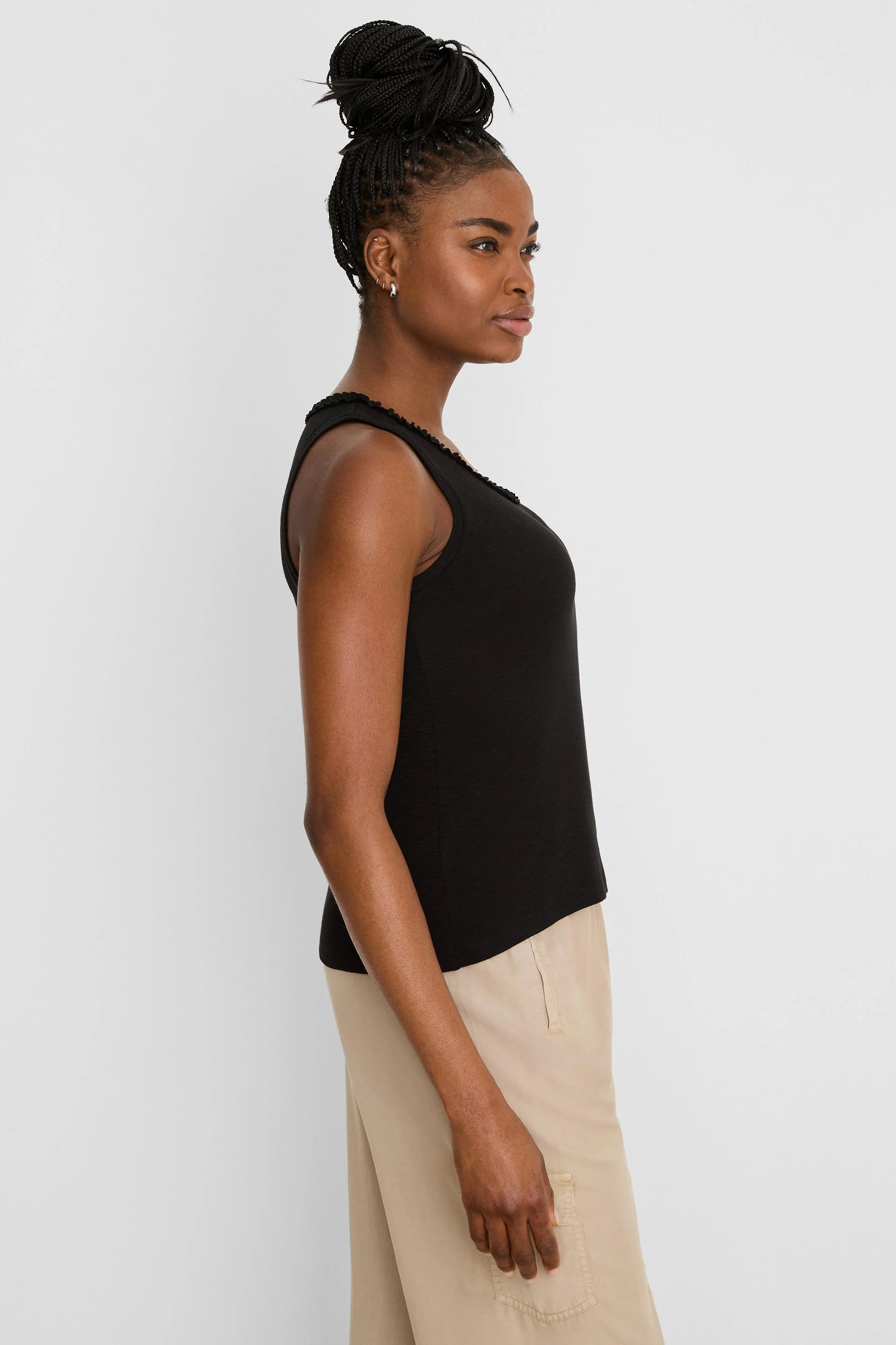 Black cotton slub tank top with a ruffled neckline, worn by a model from the side.