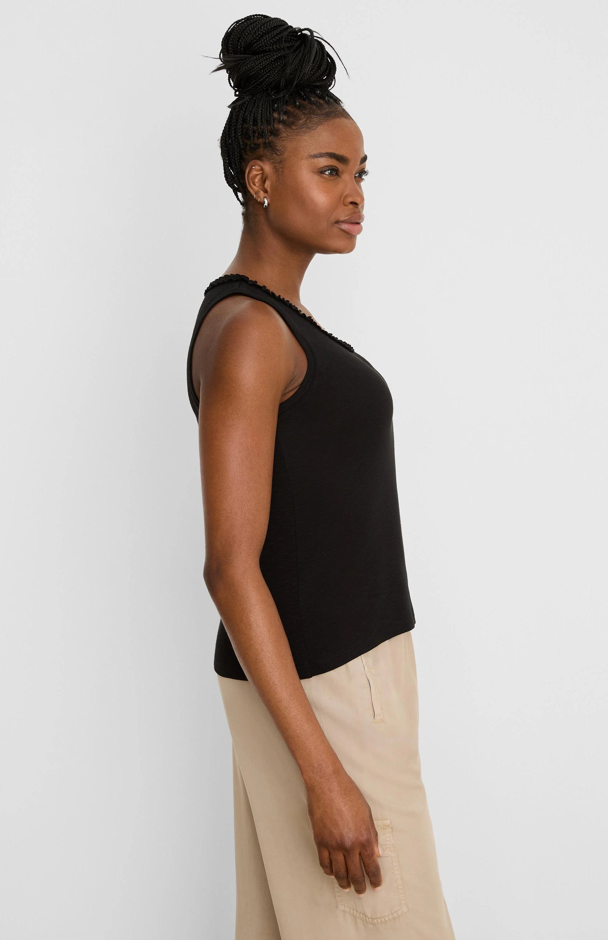 Black cotton slub tank top with a ruffled neckline, worn by a model from the side.