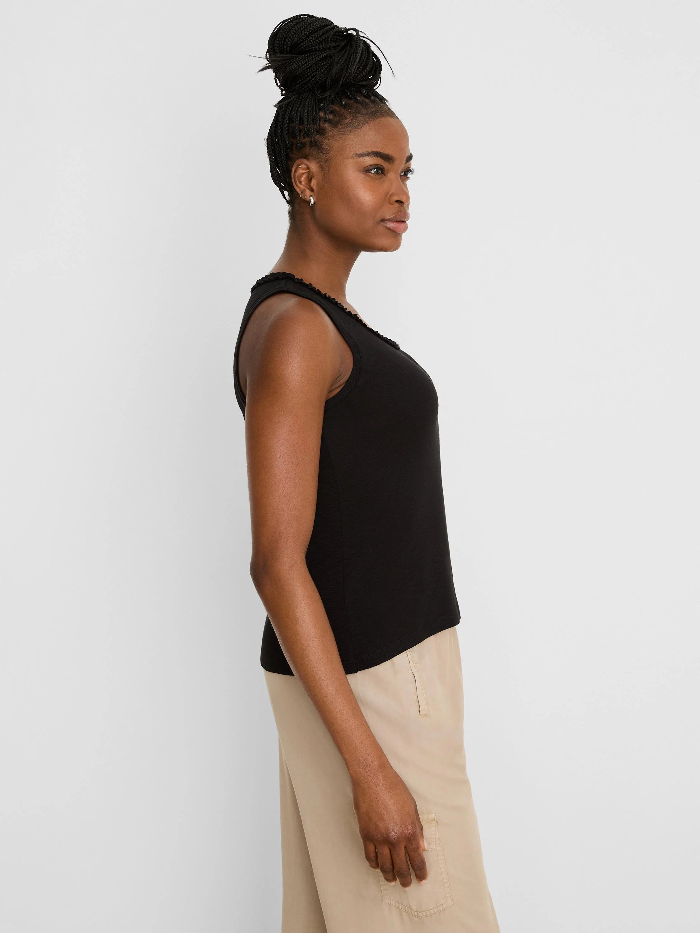 Black cotton slub tank top with a ruffled neckline, worn by a model from the side.