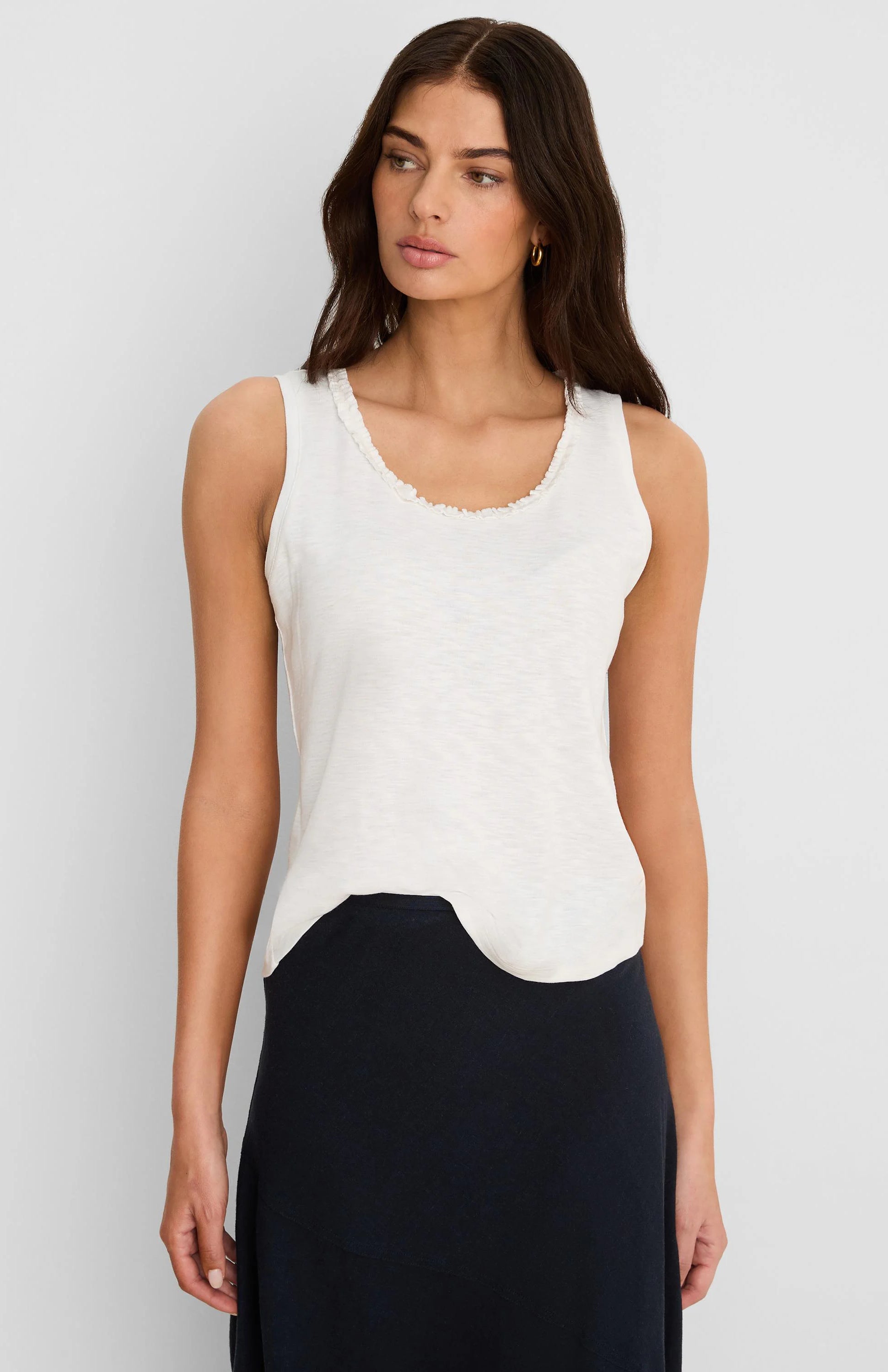 Off-white cotton slub tank top with ruffled neckline and curved hem.