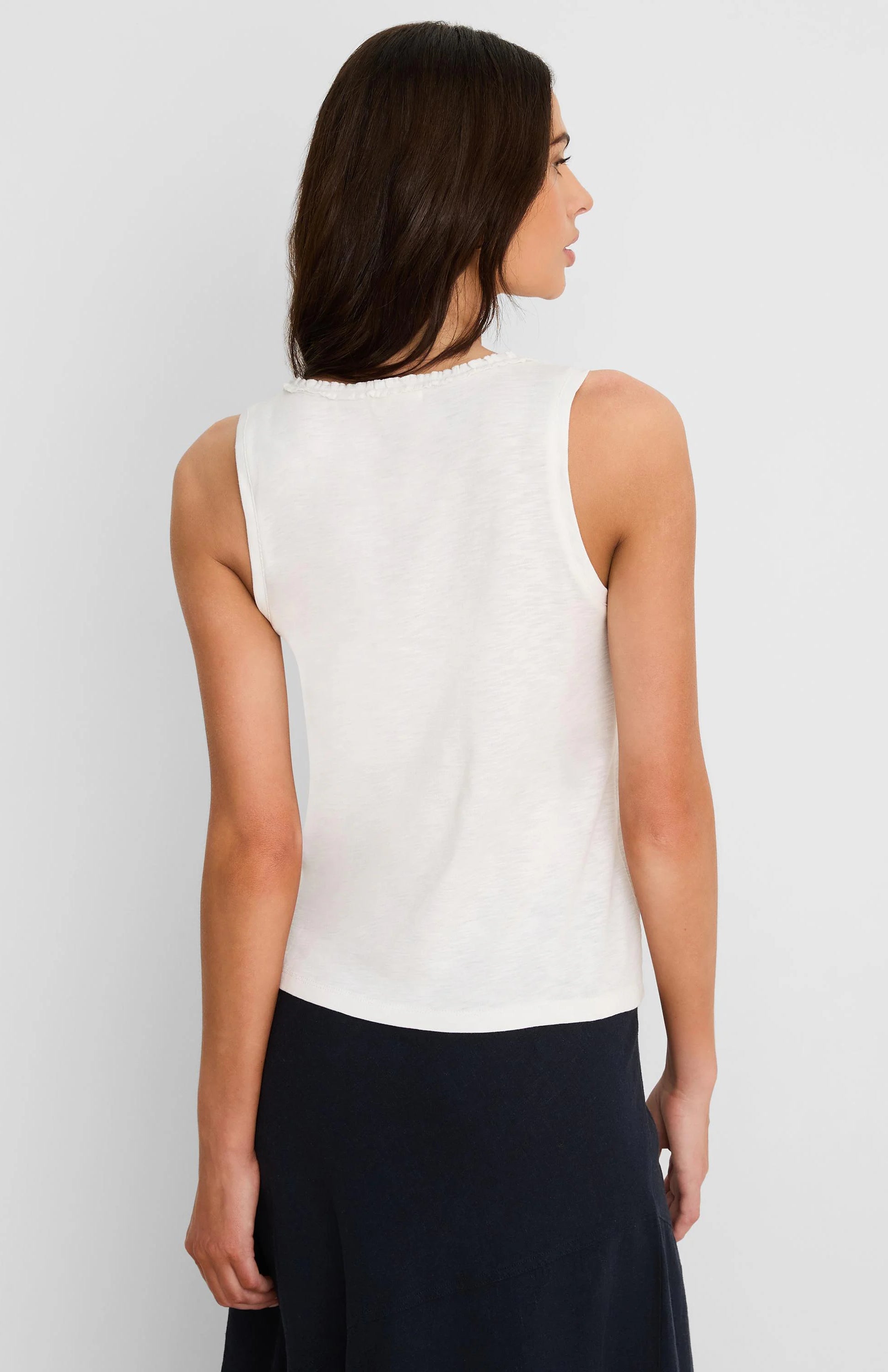 Off-white cotton slub tank top with a ruffle neck, seen from the back on a model.