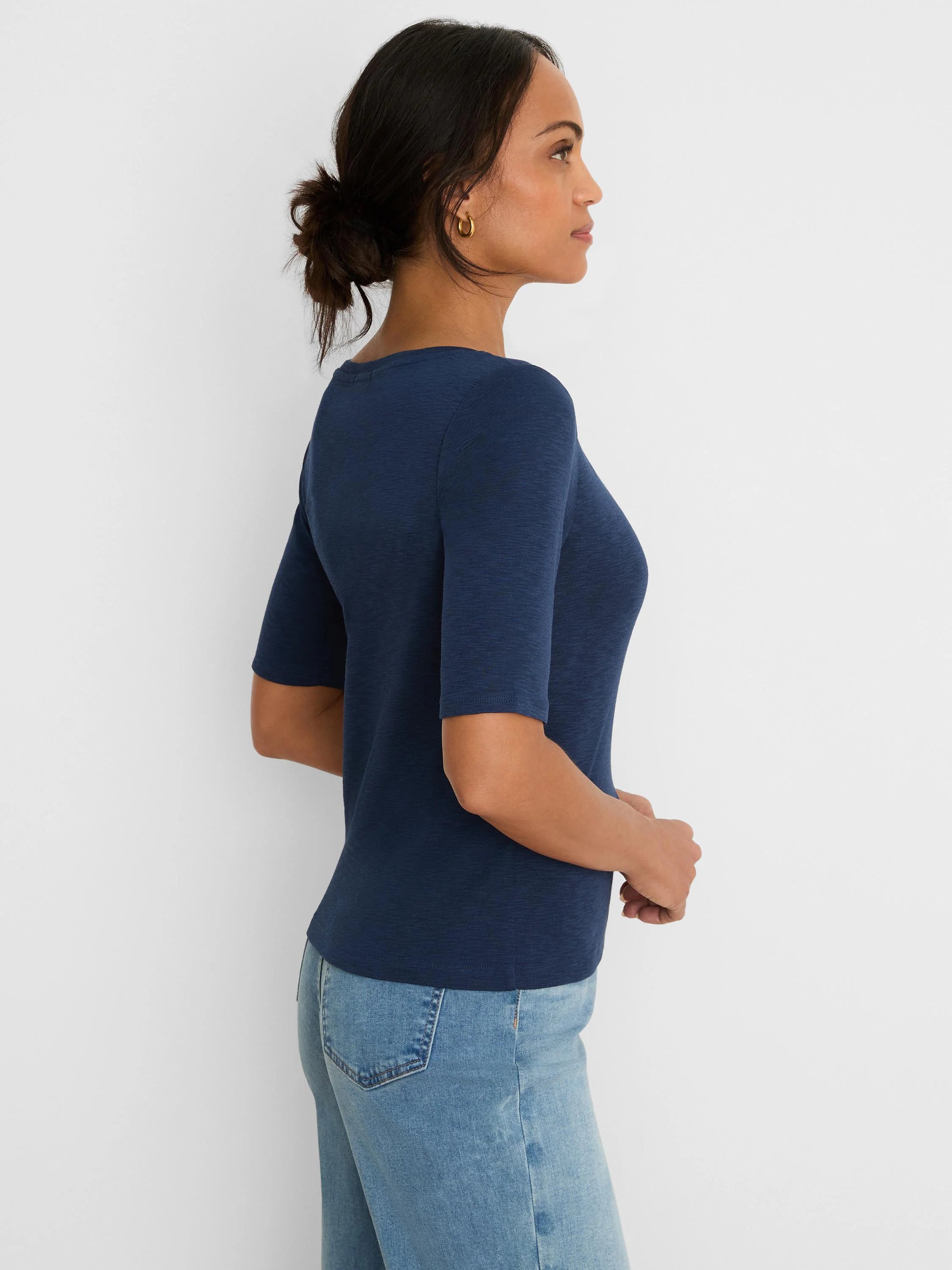 Navy fitted elbow-sleeve notch tee with a subtle V-neckline, worn by a woman in a side profile view.