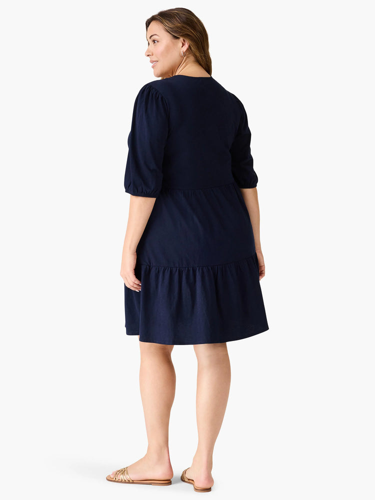 Navy blue tiered V-neck dress, 3/4 sleeves, below-knee length. Model shown from behind.