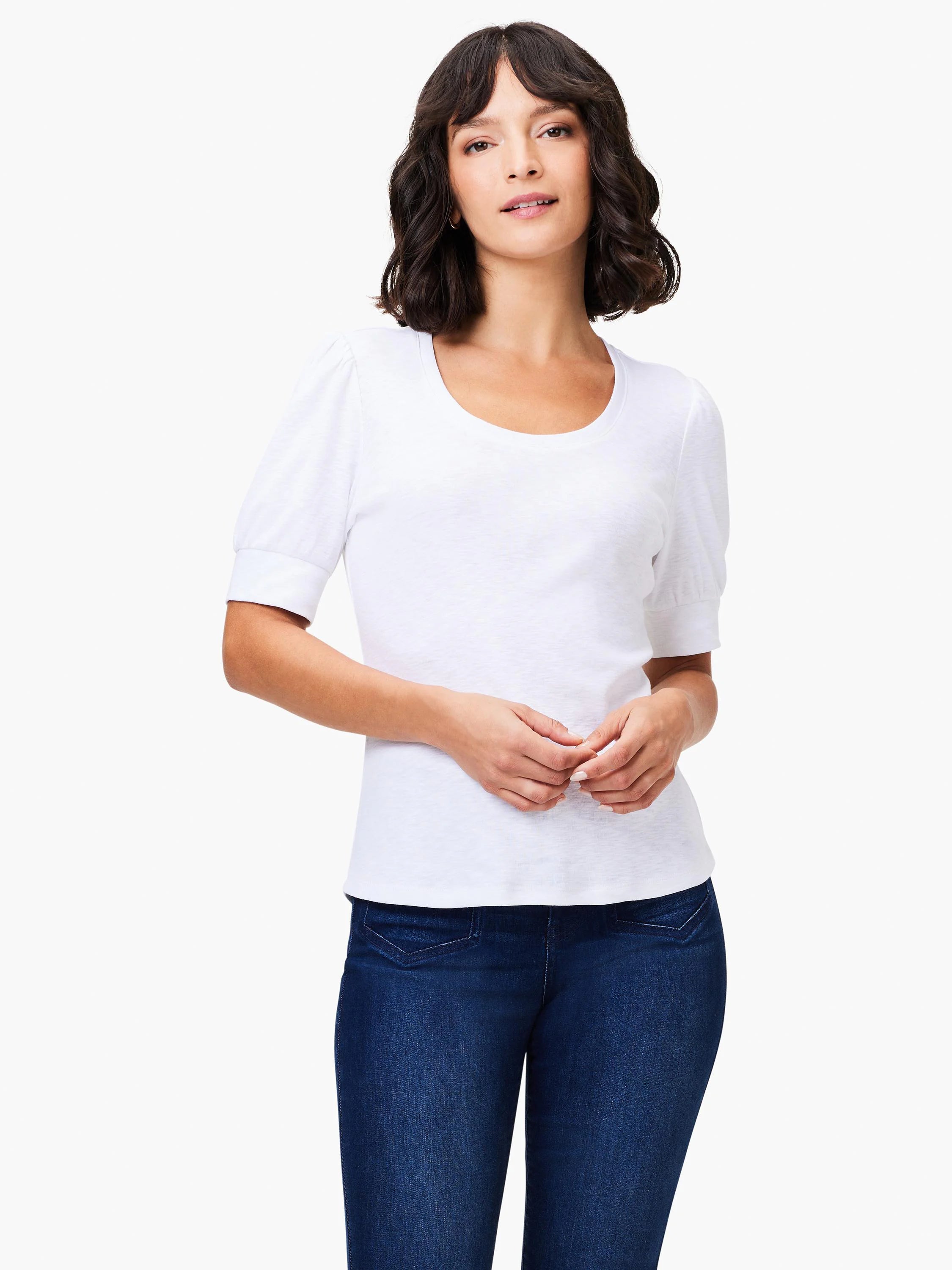 White scoop-neck tee with short, puffed sleeves. Model wears dark wash jeans.