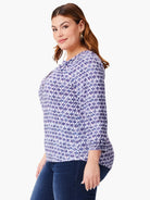 White top with a repeating purple and blue medallion pattern. Three-quarter sleeves.  Split neckline.