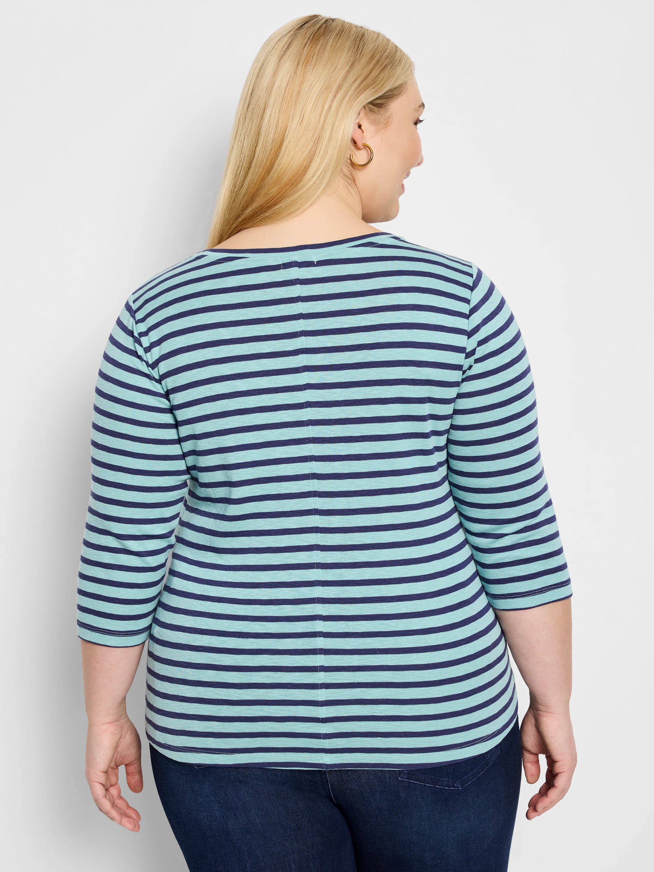 Back view of a model in a light blue and navy horizontal striped 3/4 sleeve boat neck tee with a vertical back seam.