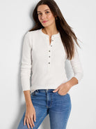 Off-white ribbed henley shirt with long sleeves and a placket of dark buttons.  Scalloped sleeve hems.