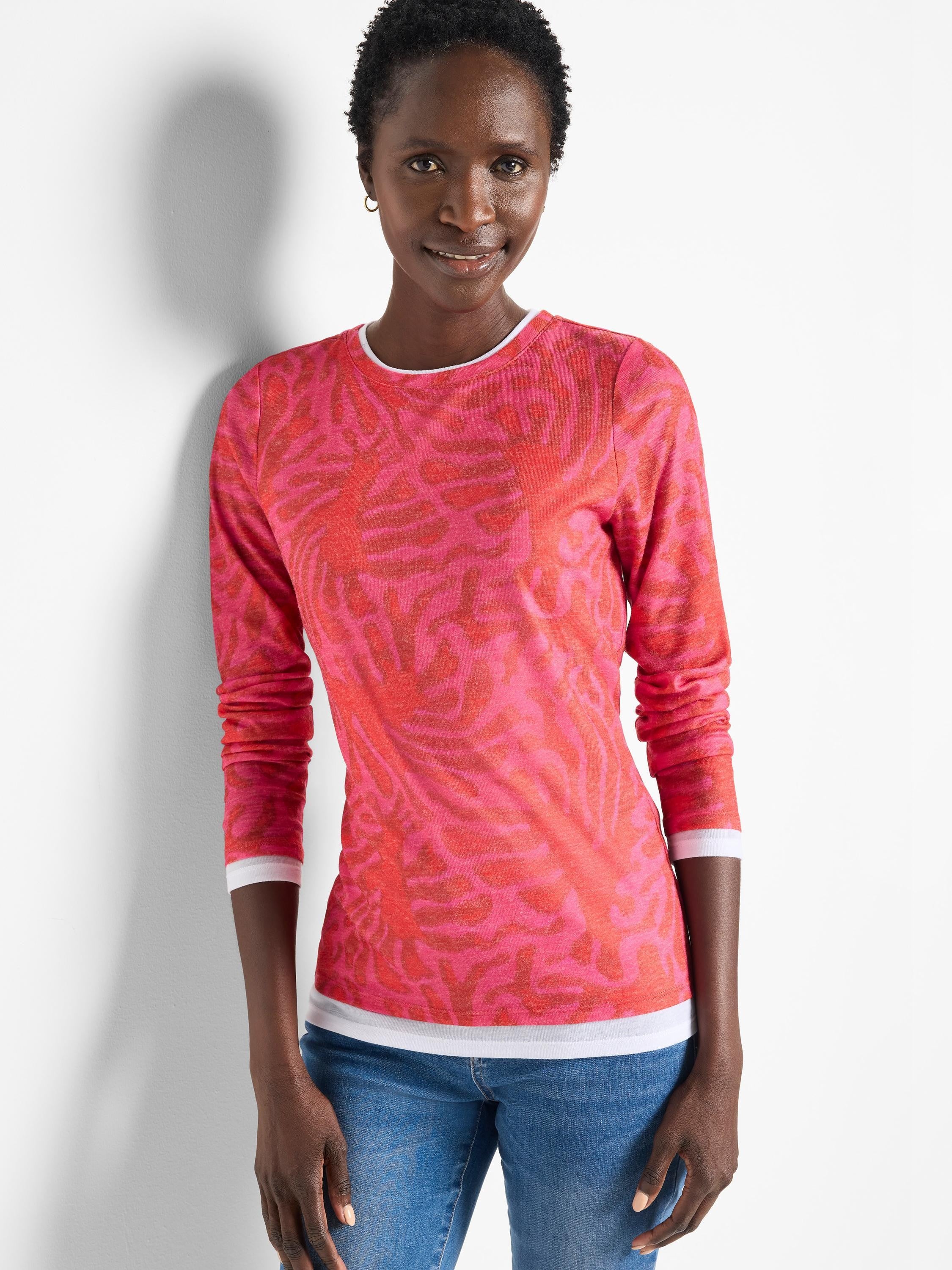Pink long-sleeve top with a darker pink leaf pattern.  Double layered at the cuffs and hem; white inner layer shows.