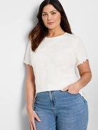 Off-white textured knit t-shirt with scalloped short sleeves.