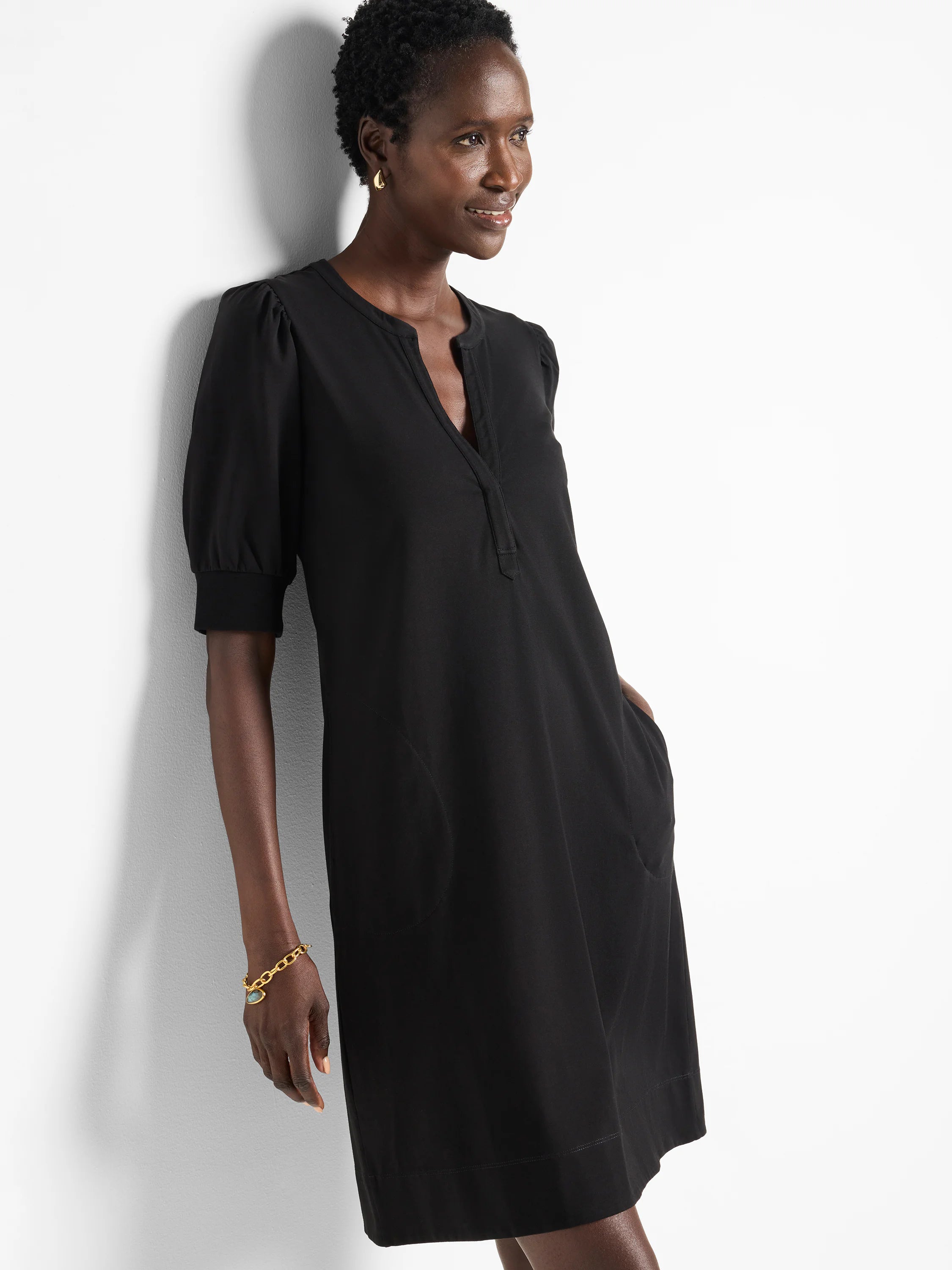 Black Henley dress, short sleeves with slight puff, V-neckline, and side pockets.