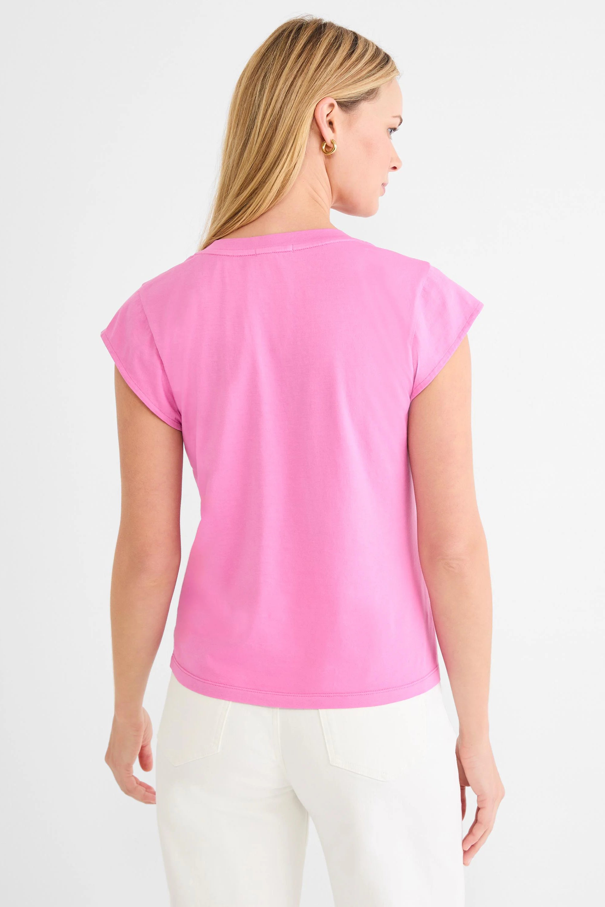 Pink cap sleeve tee, back view, worn by a model in white pants.