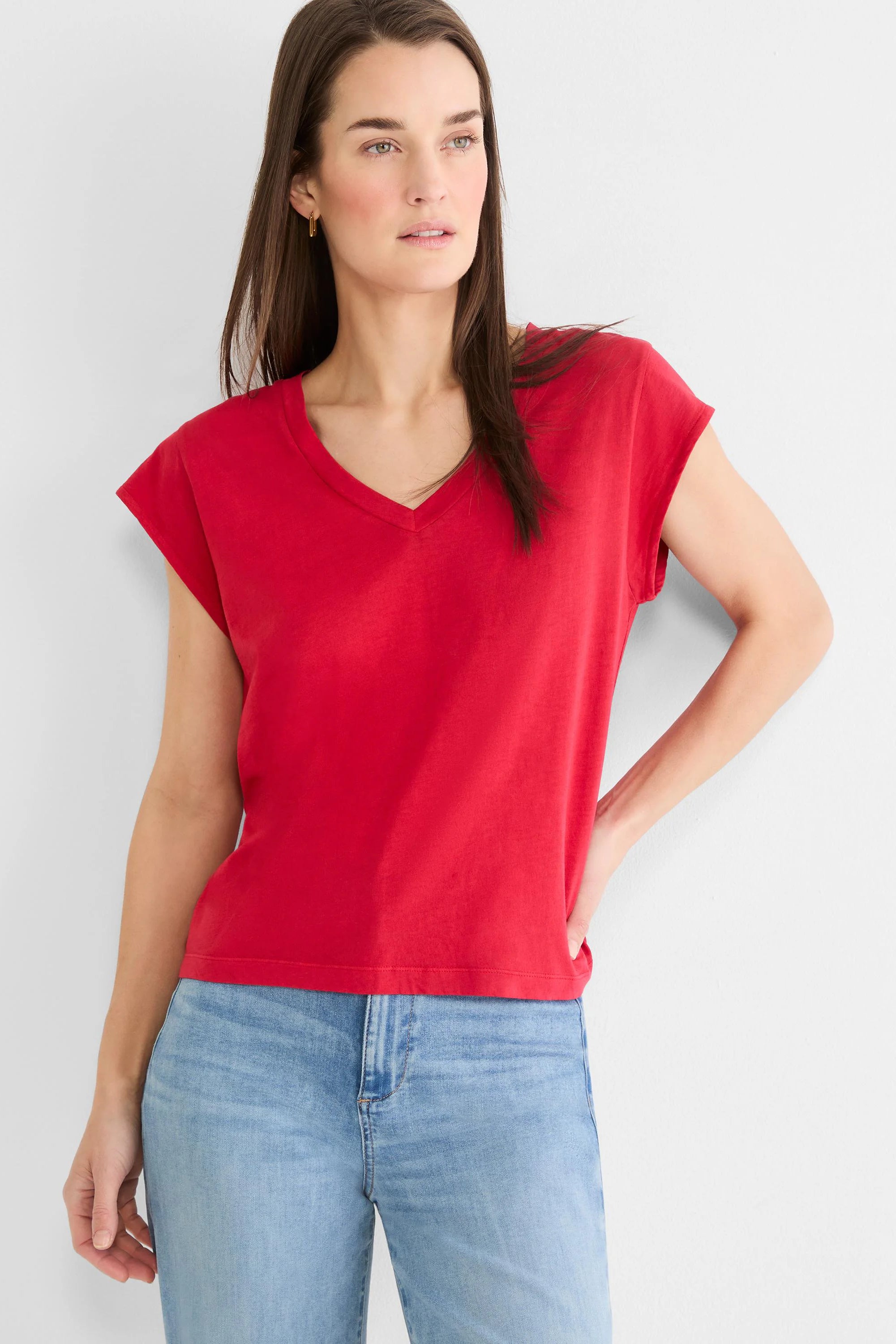Red V-neck tee with cap sleeves, worn by a woman with dark hair and light blue jeans.