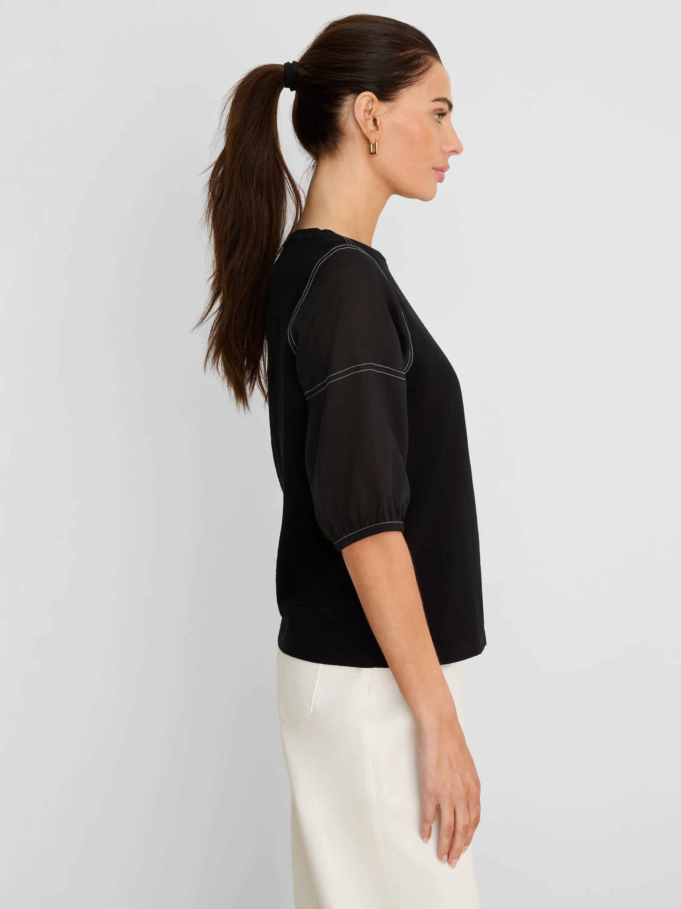 Black tee with sheer, puffed mid-length sleeves and white contrast stitching on shoulders and cuffs.