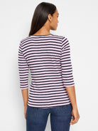 Back view of model wearing a 3/4 sleeve boat neck tee with horizontal pink and navy blue stripes.
