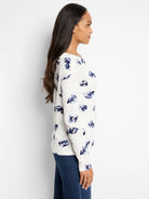 Off-white waffle-knit long-sleeve shirt with a scattered blue floral pattern.  Slight off-shoulder neckline.