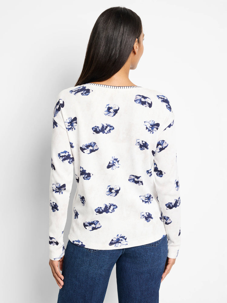 White waffle-knit long-sleeve shirt with a scattered blue floral pattern. Features a subtle neckline detail.