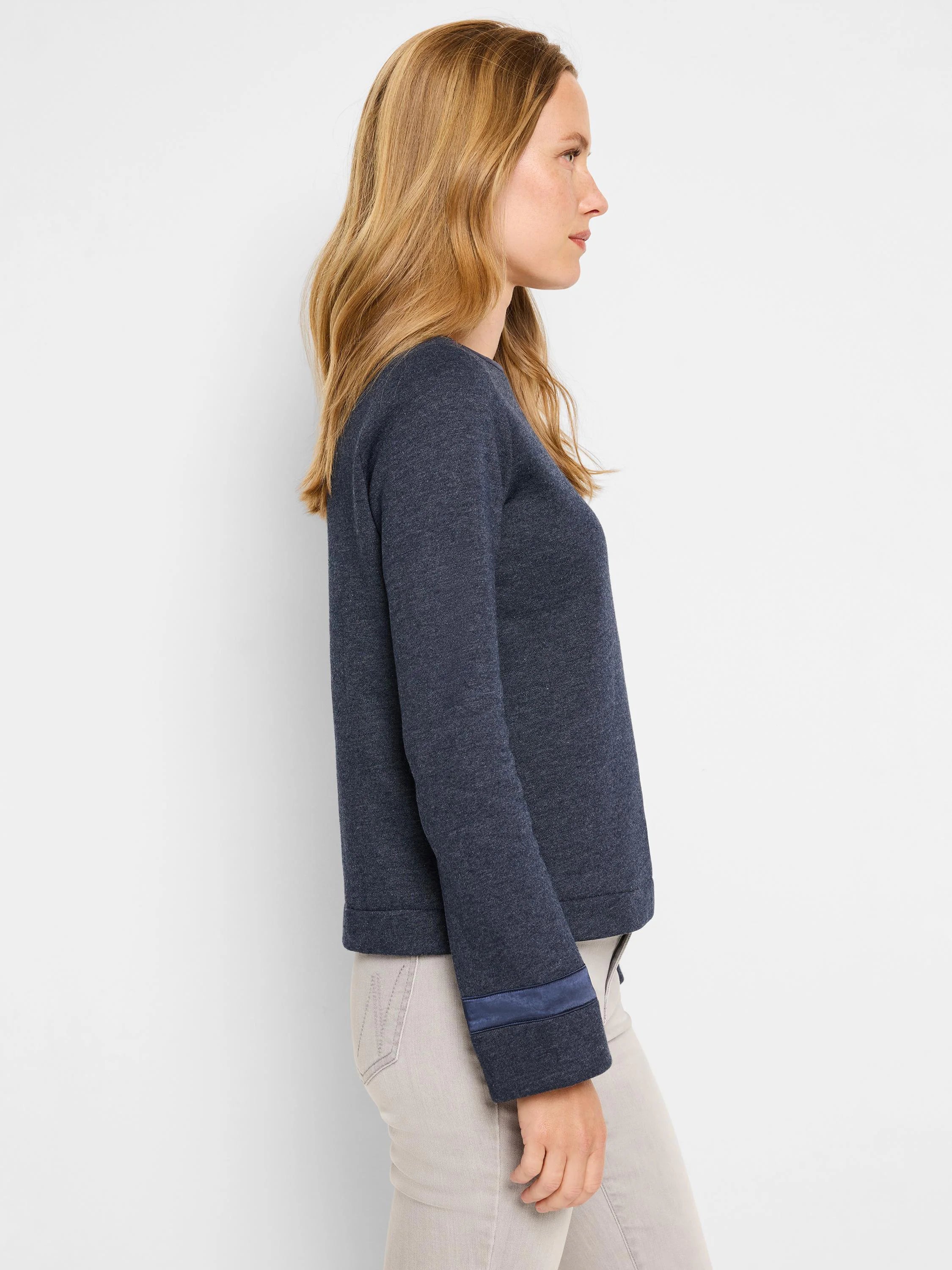 Dark blue knit top with darker blue ribbon trim at cuffs.  Side profile view.