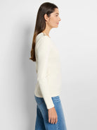 Off-white long-sleeve top with gold buttons on the shoulder.  Side profile view.