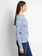 Off-white top with blue diamond pattern, long sleeves, and gold buttons on the shoulders.