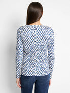 Long-sleeve top, off-white background with blue diamond pattern.  Gold buttons on shoulders.