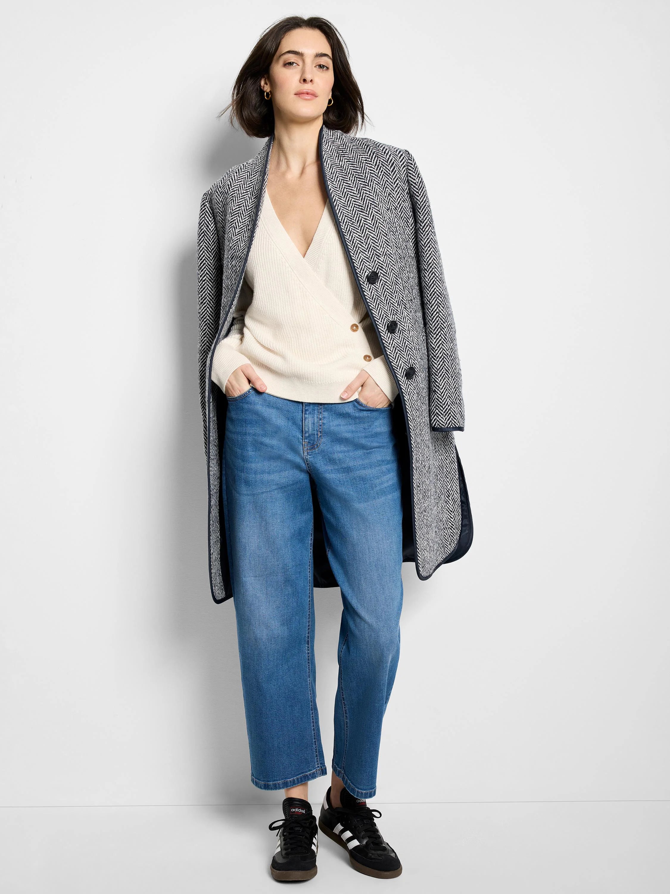 Black & white herringbone pattern top coat, dark navy trim.  Model wears it over a cream sweater and blue jeans.