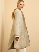 Cream and light brown herringbone wool blend top coat with taupe piping along edges and side vents. Worn open.