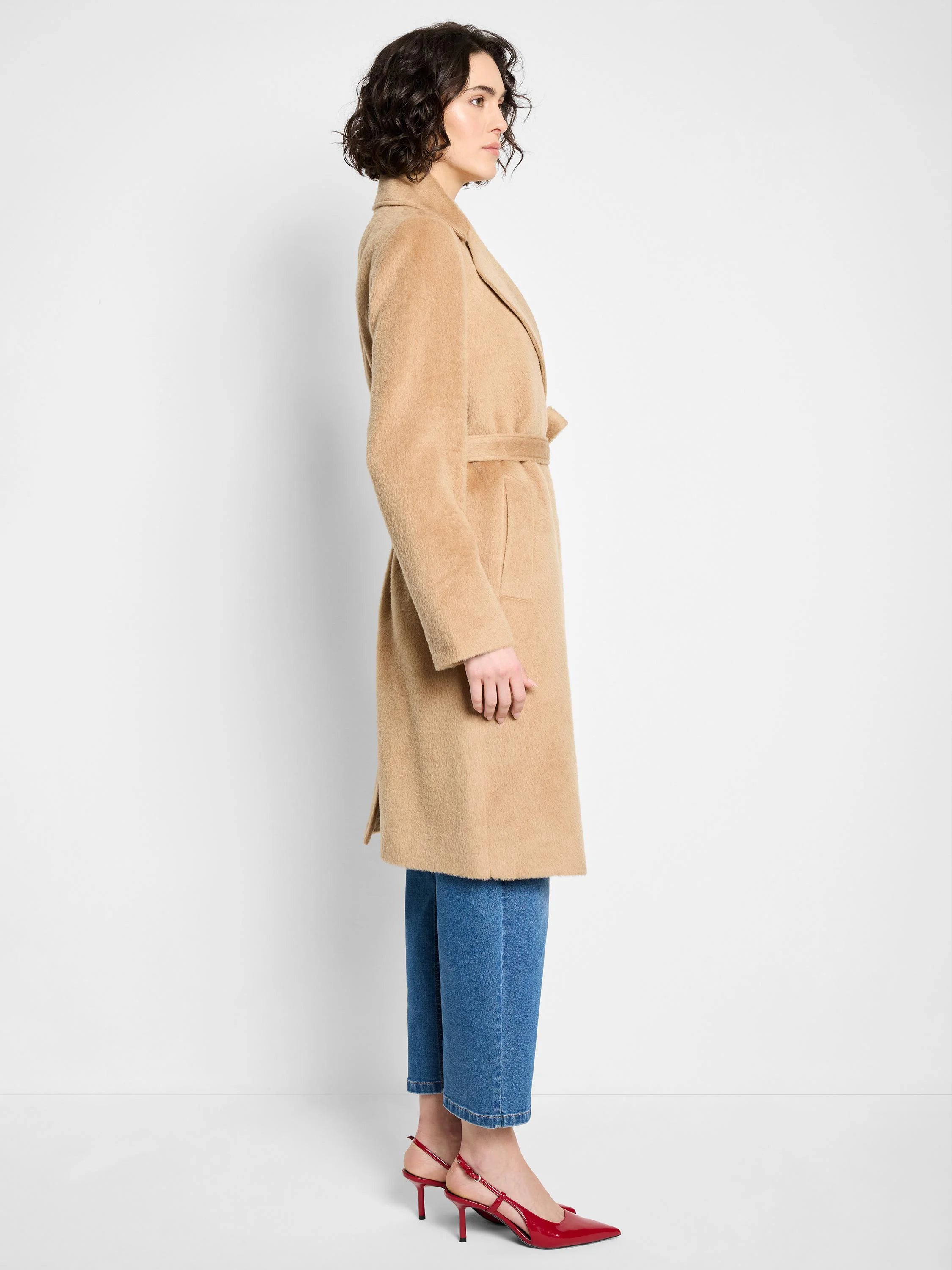 Beige belted wrap coat, knee-length.  Textured fabric. Model shown wearing blue jeans and red shoes.