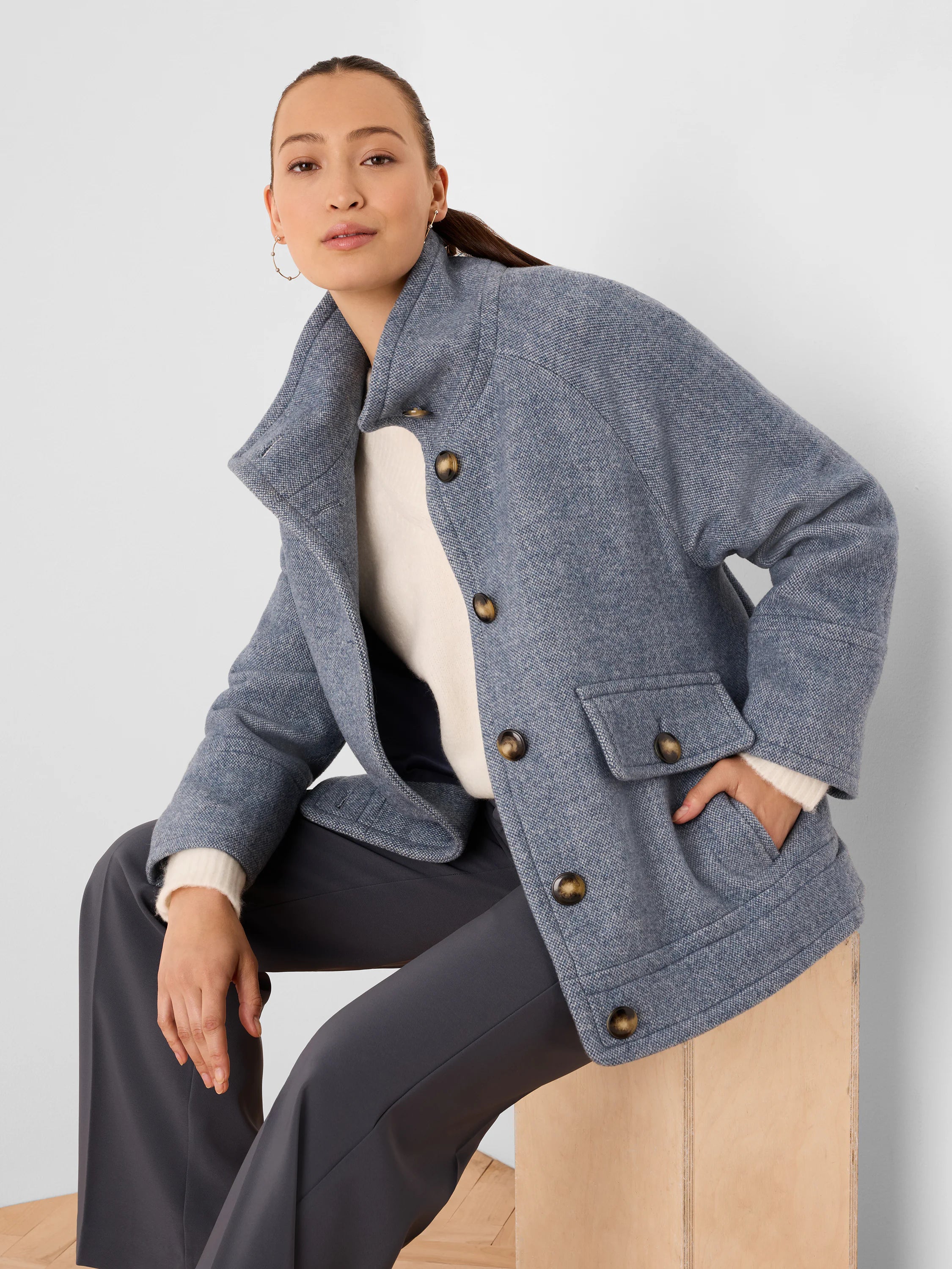 Blue heathered wool coat with a high collar, brown buttons, and two front flap pockets.