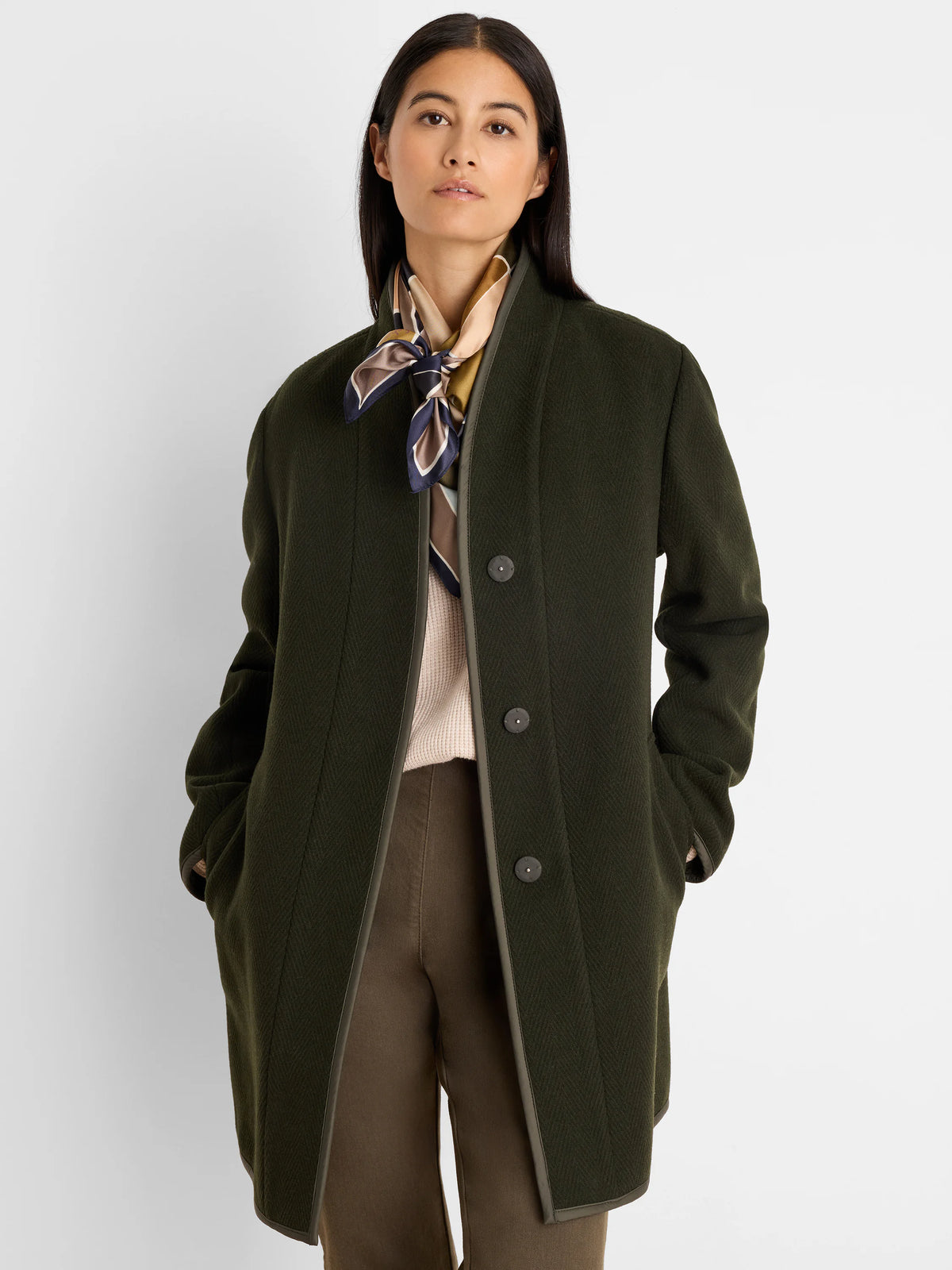 Dark green reversible wool top coat, collarless, with subtle herringbone texture. Lighter olive trim and buttons.