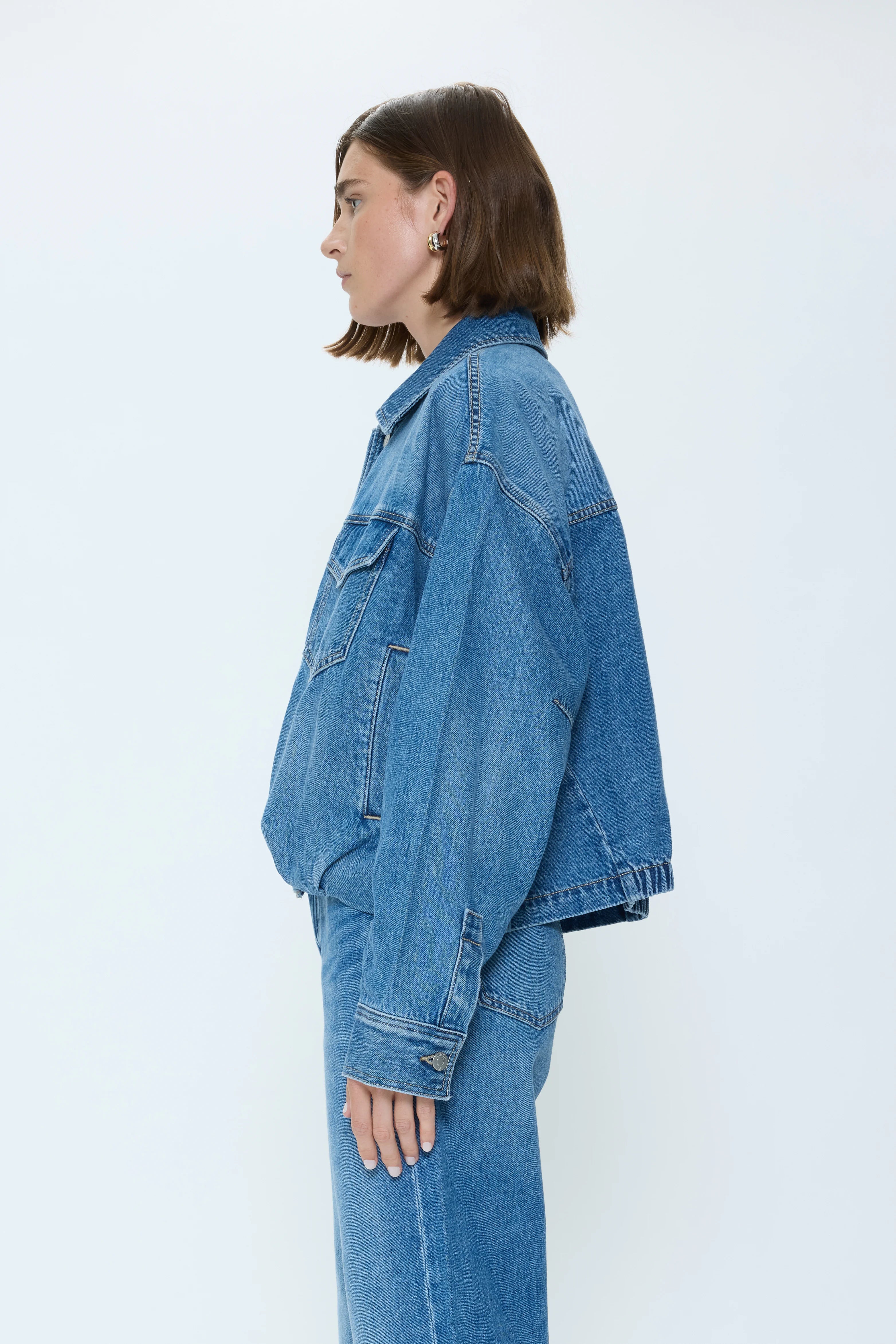 Medium blue denim blouson jacket. Features oversized fit, classic collar, flap chest pockets, and contrast stitching.