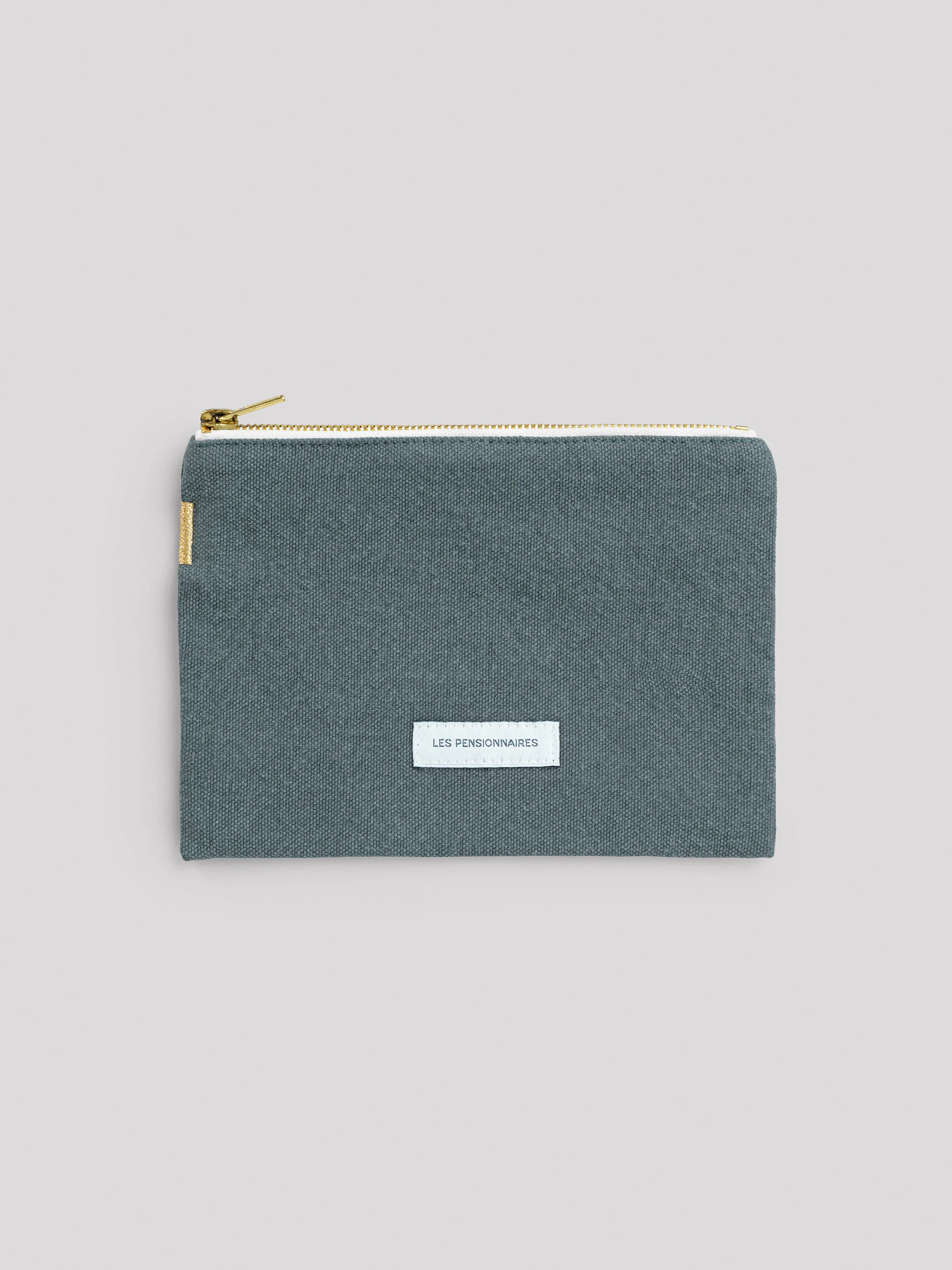 Dark teal woven cotton pouch with gold zipper and white tape, and a white 'LES PENSIONNAIRES' label.