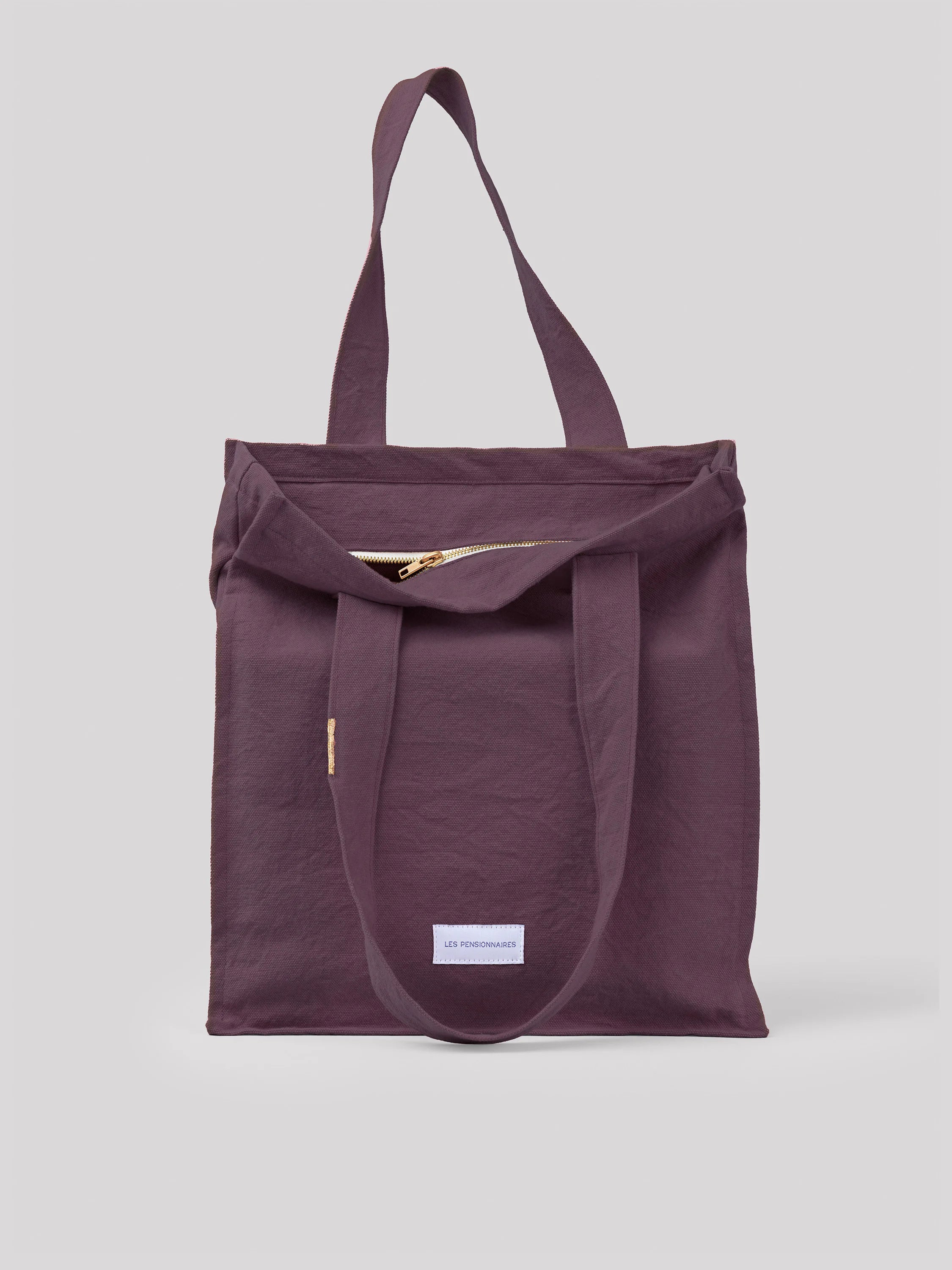 Plum cotton tote bag with two top handles, a gold zipper, and a white 'Les Pensionnaires' label.