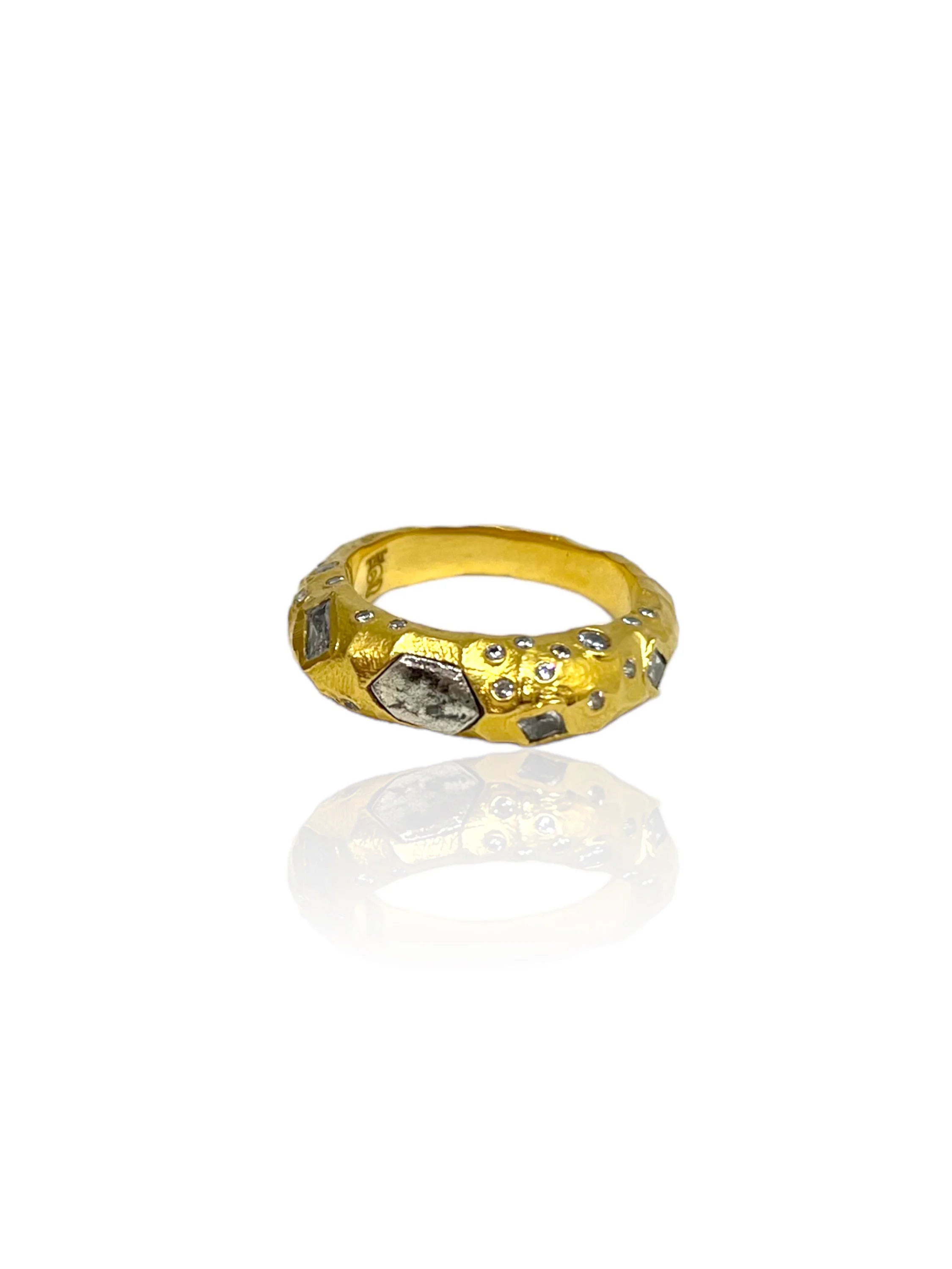 Hammered gold ring with scattered clear gems and several larger, irregular silver-toned stone inlays.