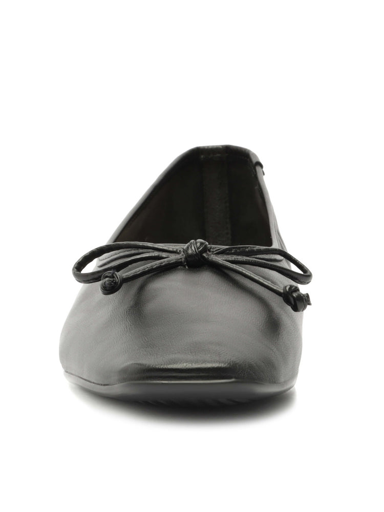 Black leather slip-on flats have a slightly square toe and a matching knotted bow detail.