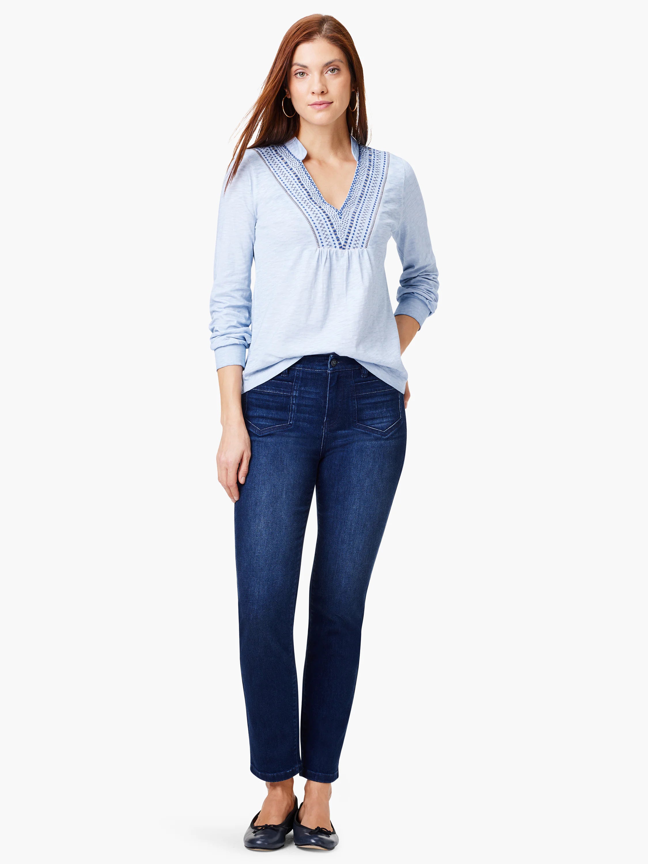 Light blue long-sleeve top with blue embroidery at neckline; model also wears dark wash jeans.