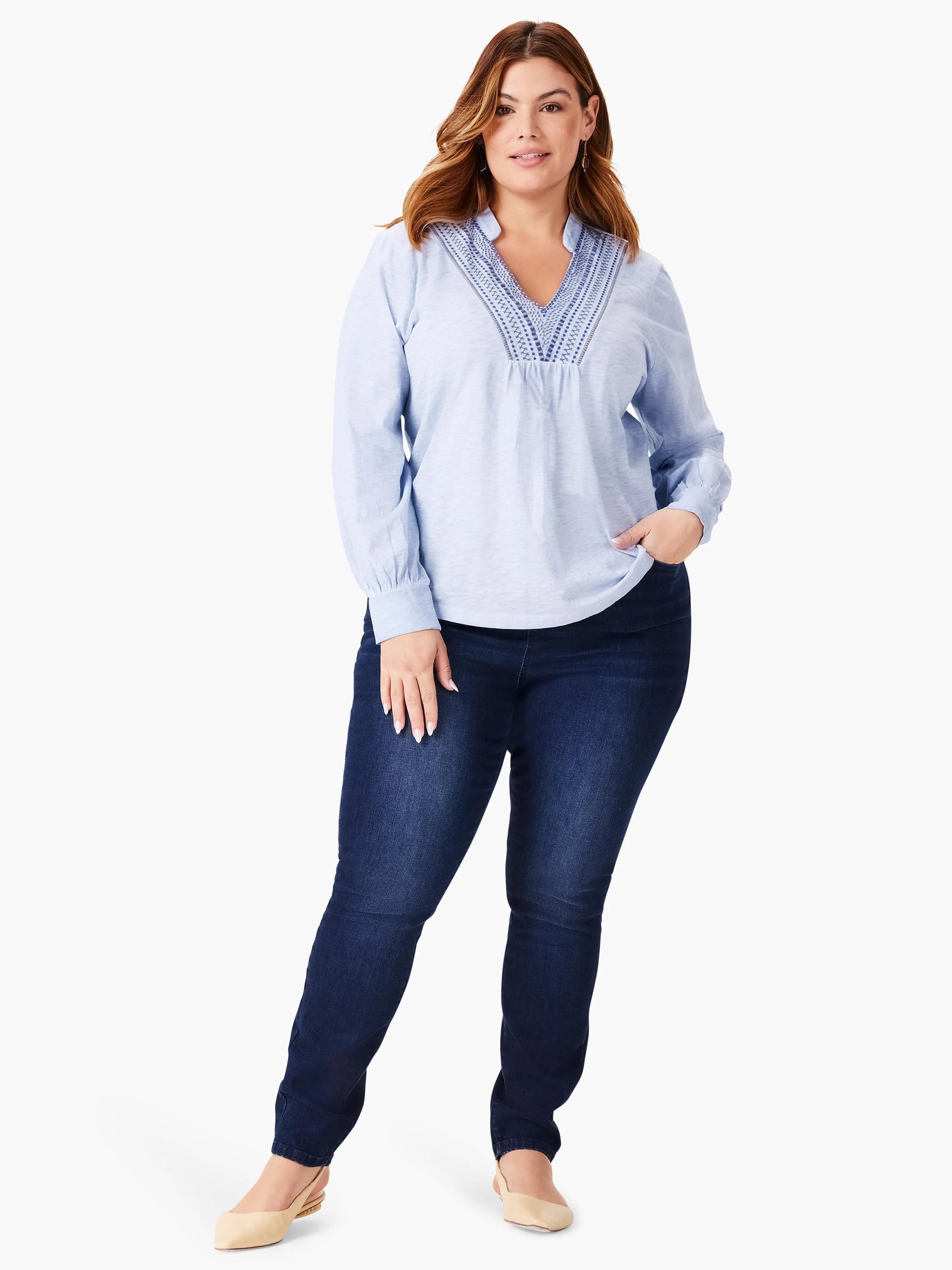 Light blue long-sleeve top with darker blue embroidery at neckline. Model wears dark wash jeans.