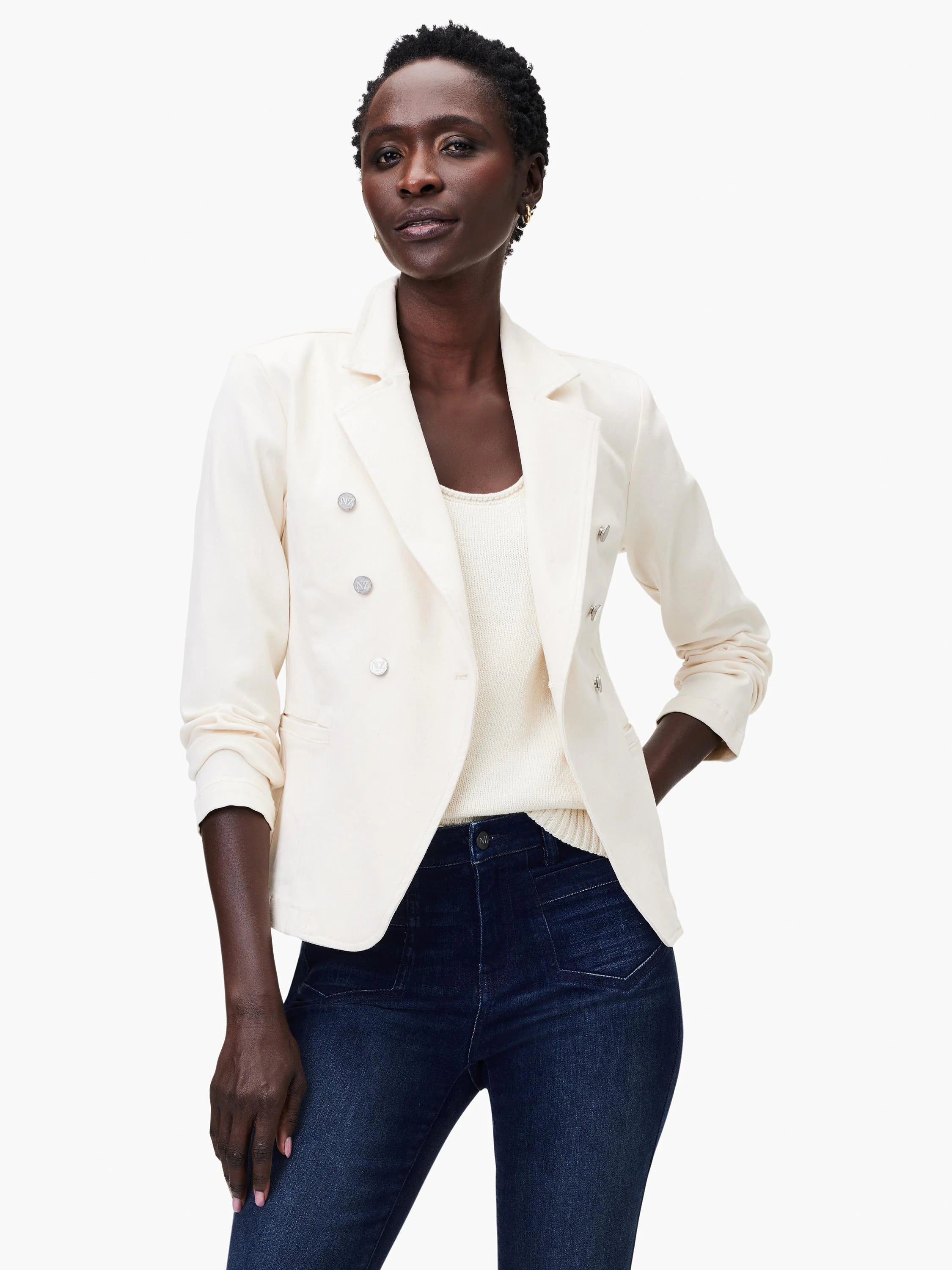 Off-white double-breasted blazer with silver buttons. Model wears it with a cream top and dark wash jeans.